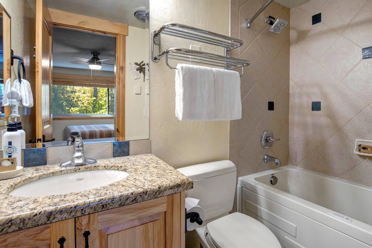 The en suite bathroom with a single sink vanity and a bathtub and shower combination.