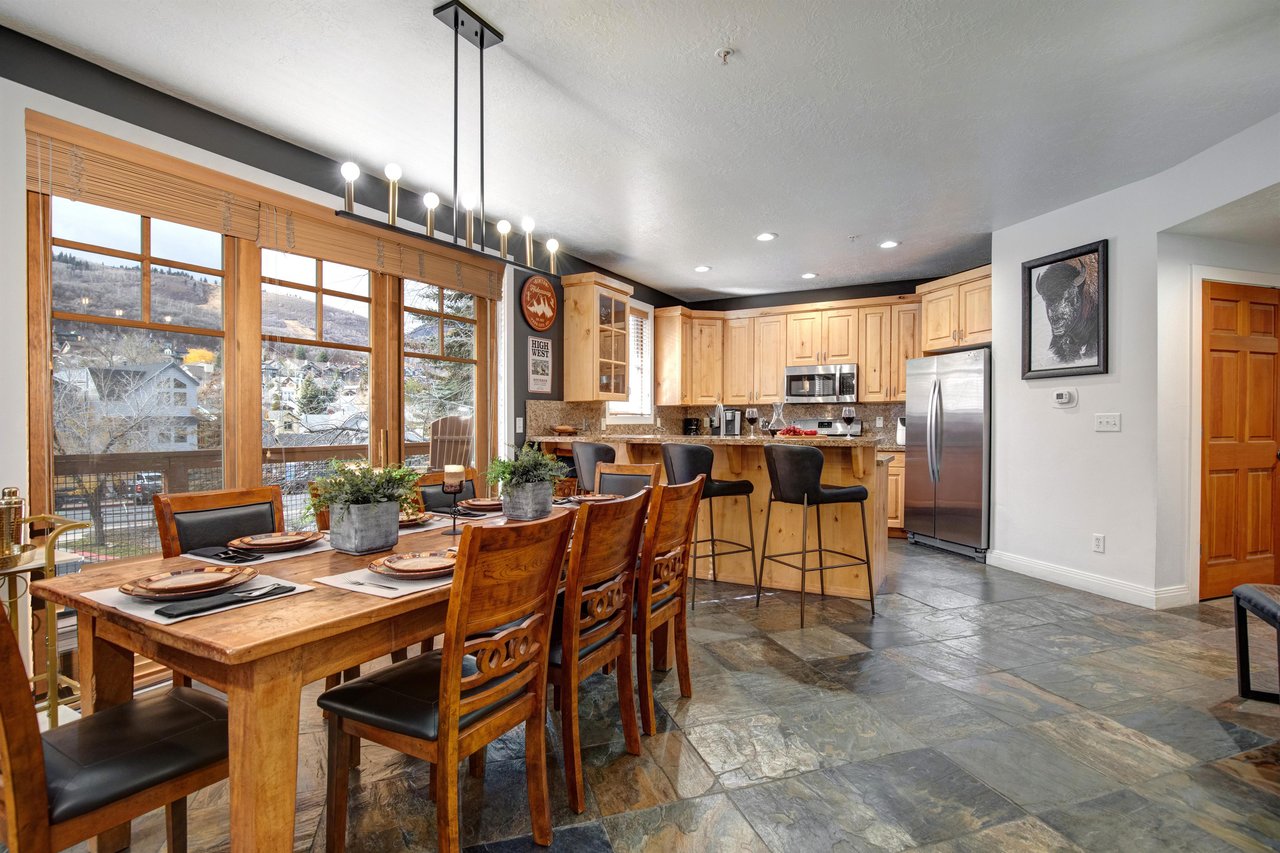 Spacious openconcept kitchen and dining area with warm wood cabinetry, modern appliances, and a welcoming breakfast bar.