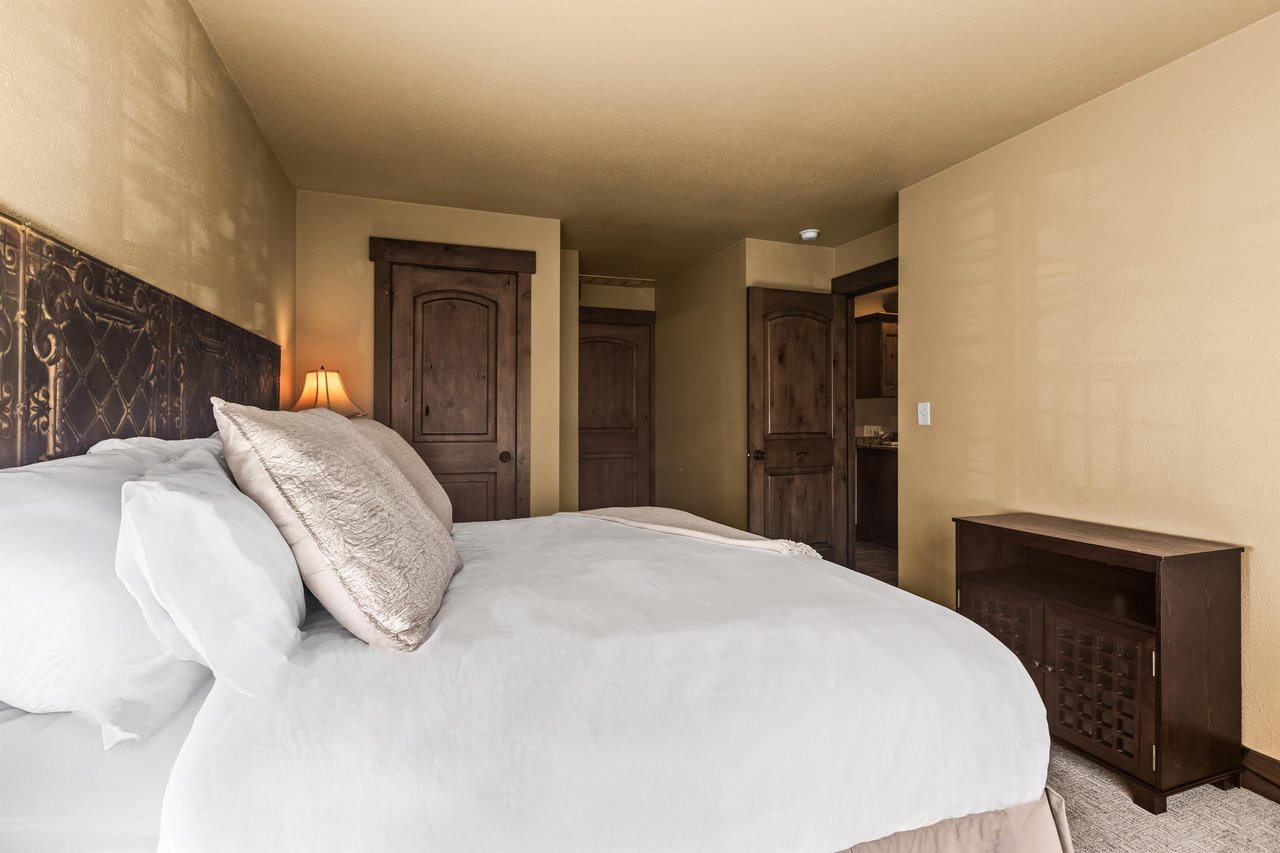 Sink into luxury in your serene bedroom, where an ornate carved headboard and plush linens create the perfect retreat.