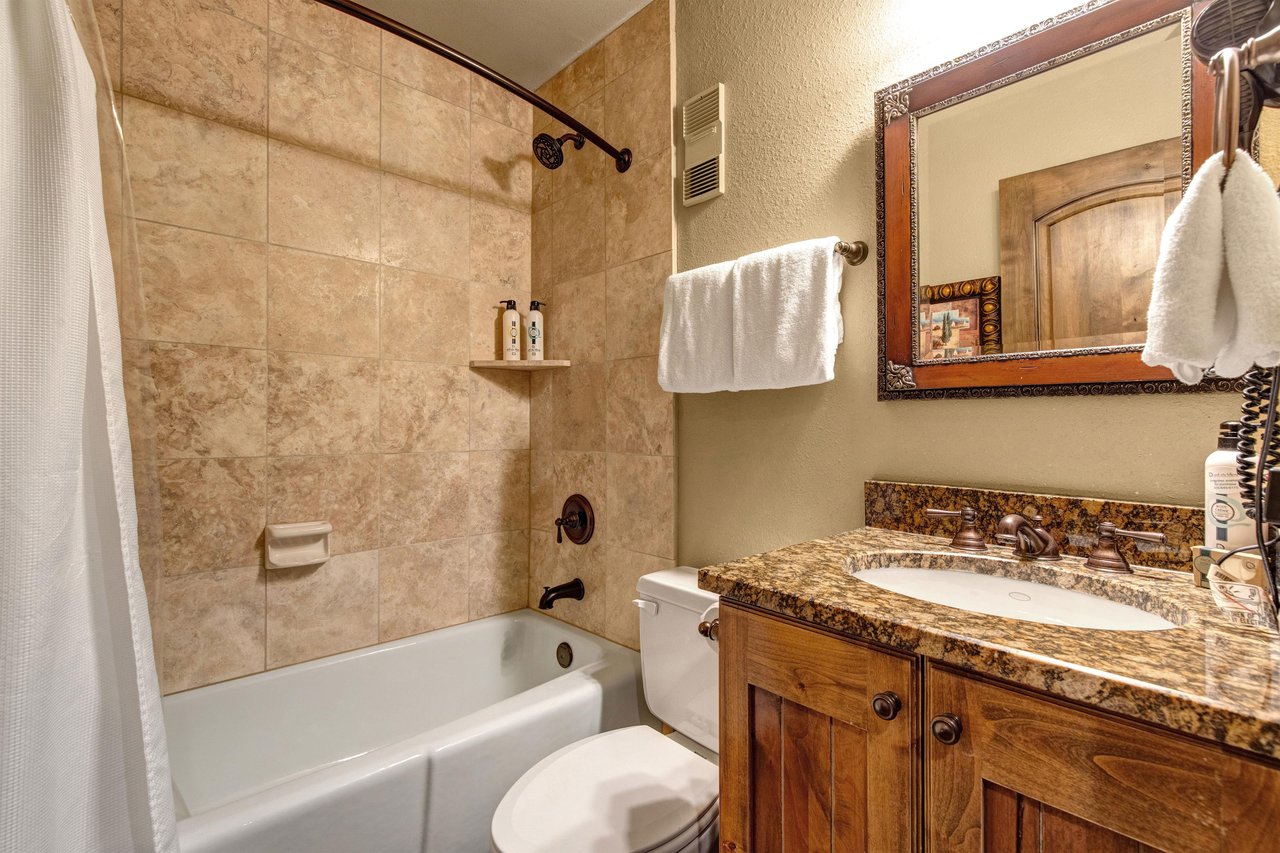 Step into your elegant marble bathroom with warm stone tiles and granite countertops .