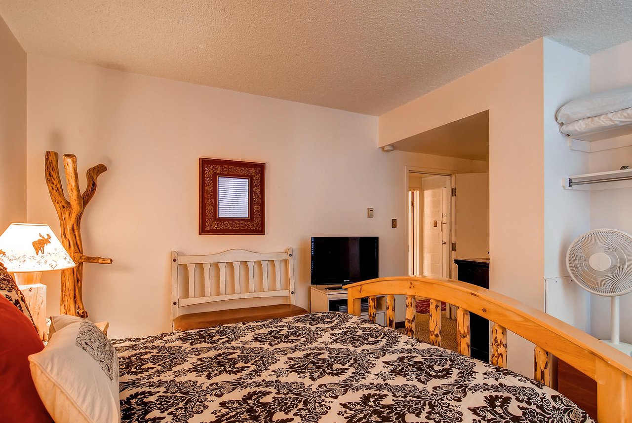 The main suite with a queen bed, TV and a bench.