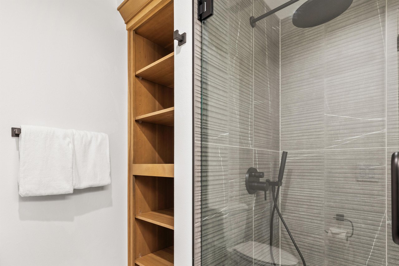 Step into your modern ensuite featuring a sleek glass shower with contemporary fixtures and convenient builtin storage for your essentials.