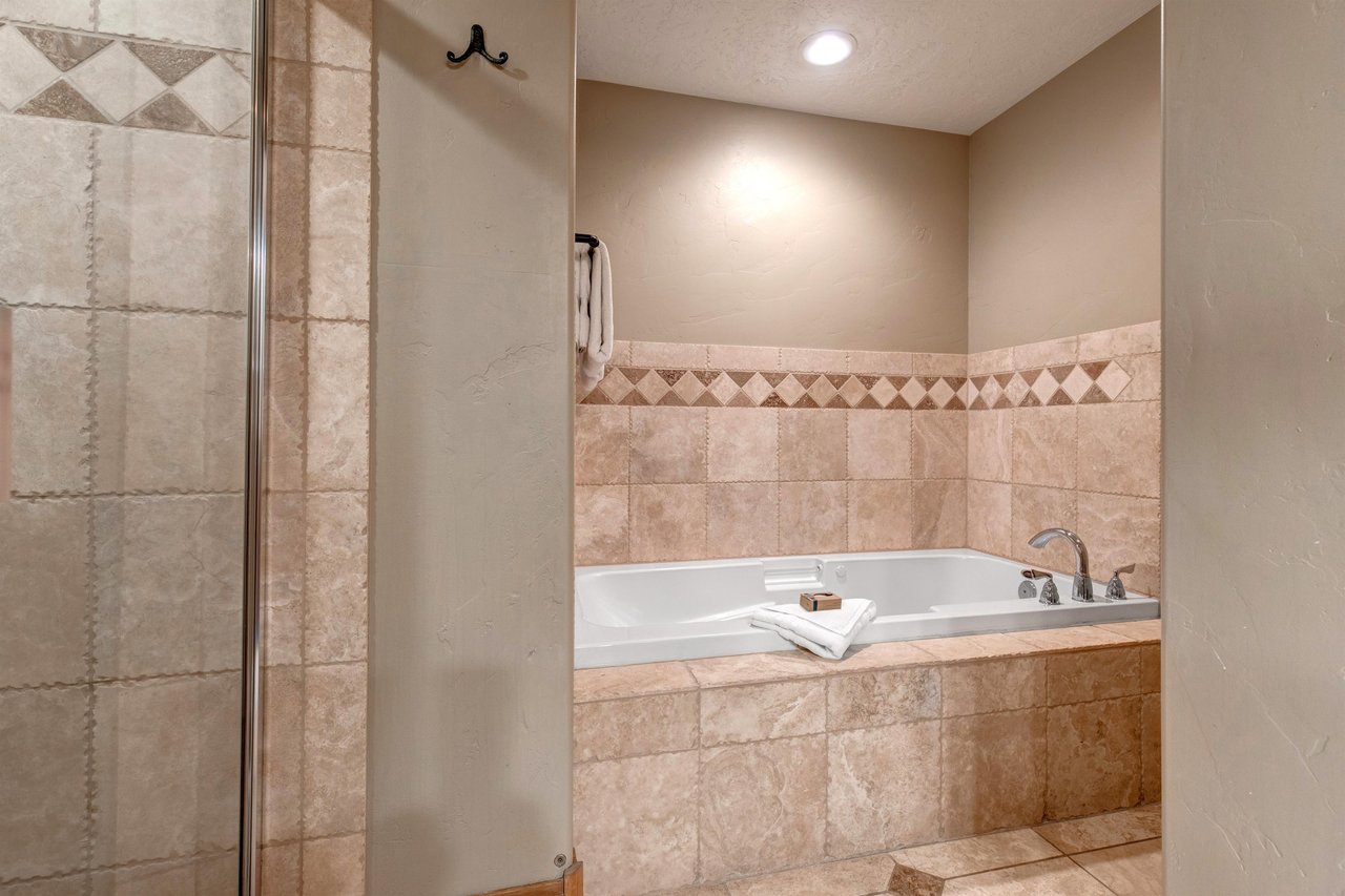 Unwind in your elegant bathroom featuring a soaking tub and separate glass shower, designed with beautiful stone tile accents for your relaxation.