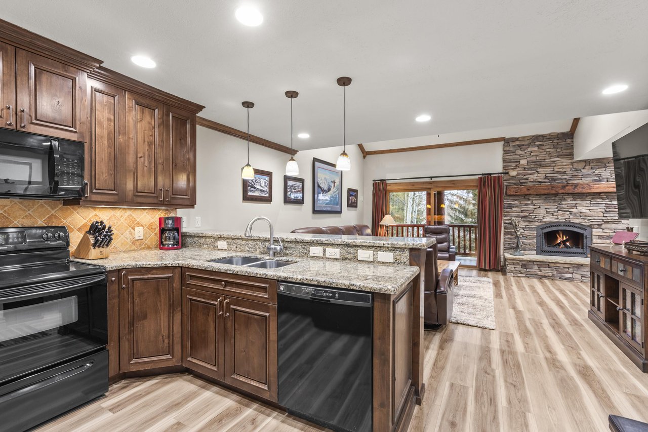 Your spacious kitchen features granite countertops, rich wood cabinets, and a cozy stone fireplace.