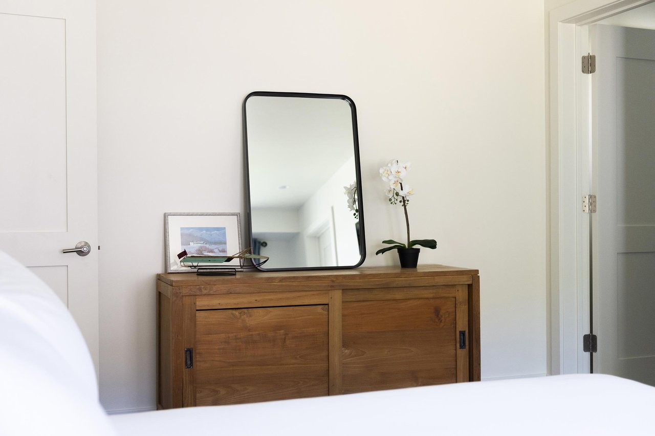 Queen guest bedroom with wooden chest and large vanity mirror