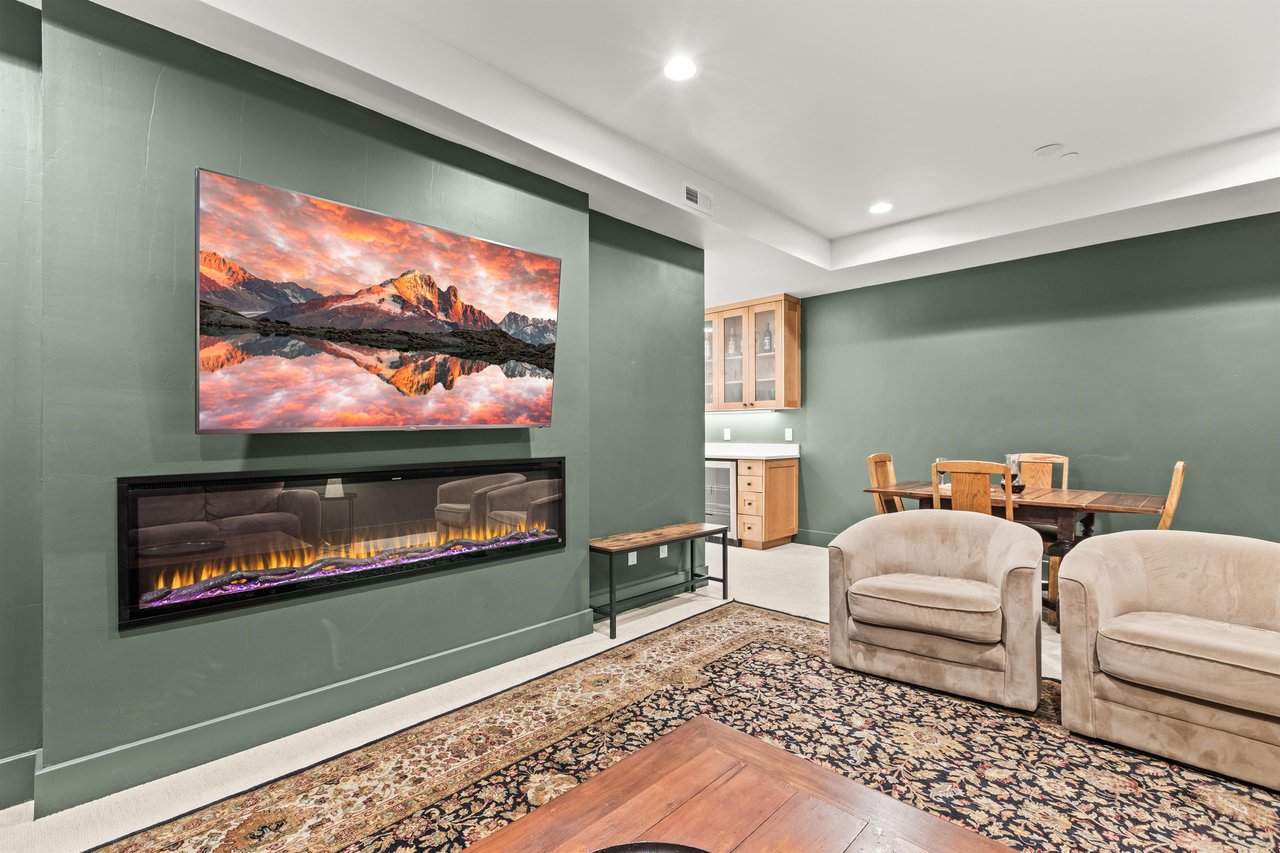 Cozy up in your elegant living space featuring a modern fireplace and large TV, perfect for relaxing evenings together.