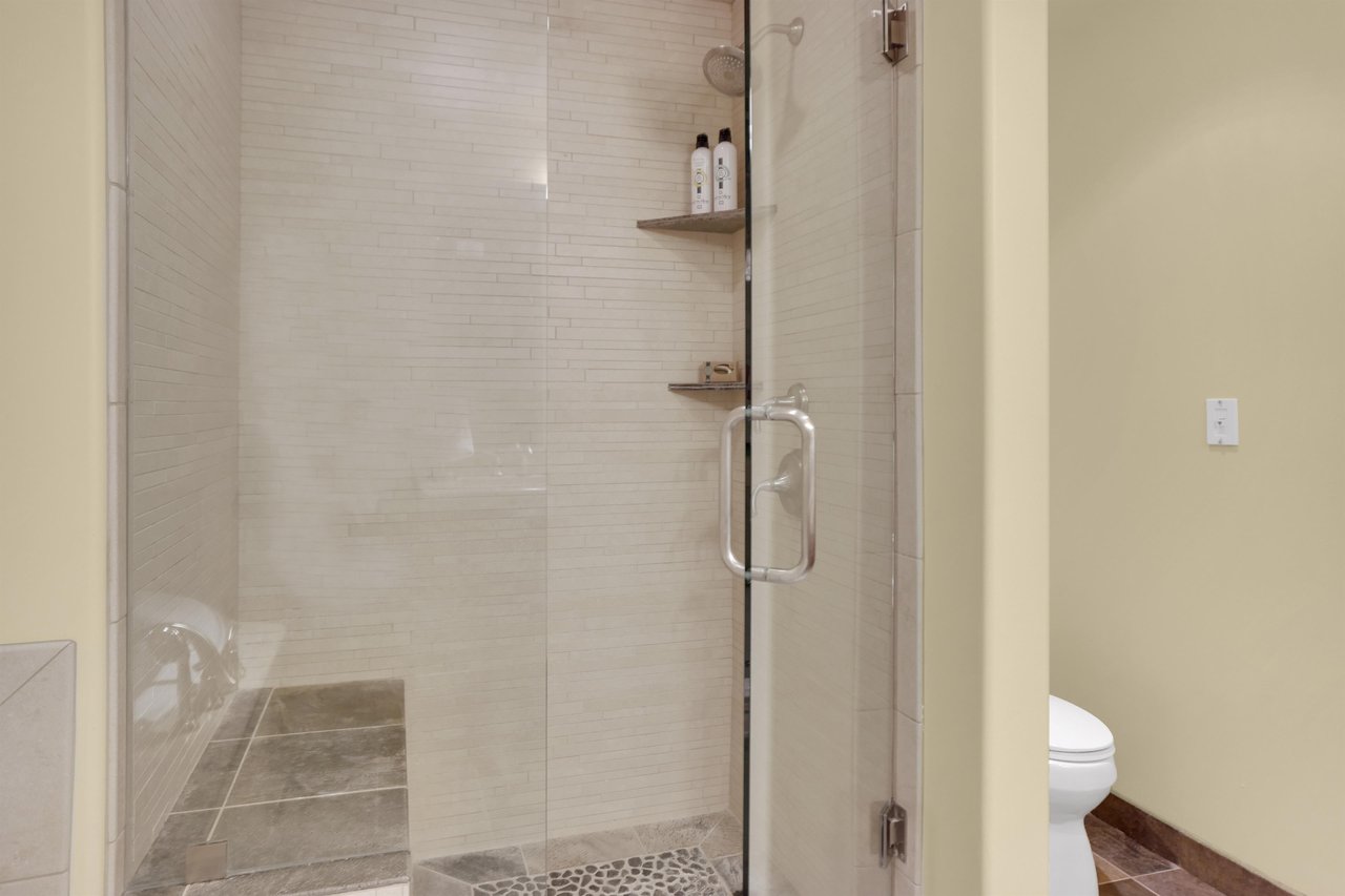 Walkin shower with tile surround, tile sitting bench, and glass enclosure.