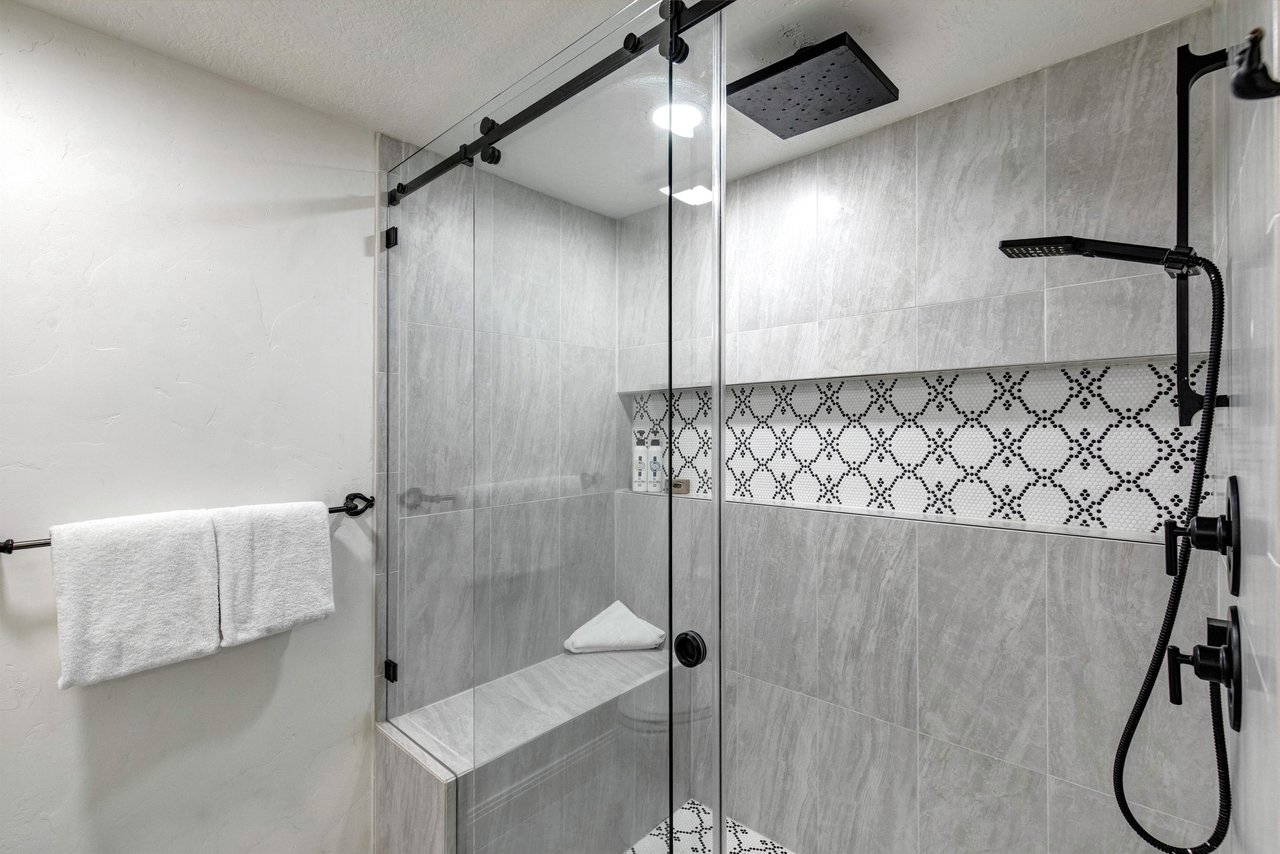 The private en suite bathroom features a spalike shower, elegant gray tiling and a builtin bench for comfort.