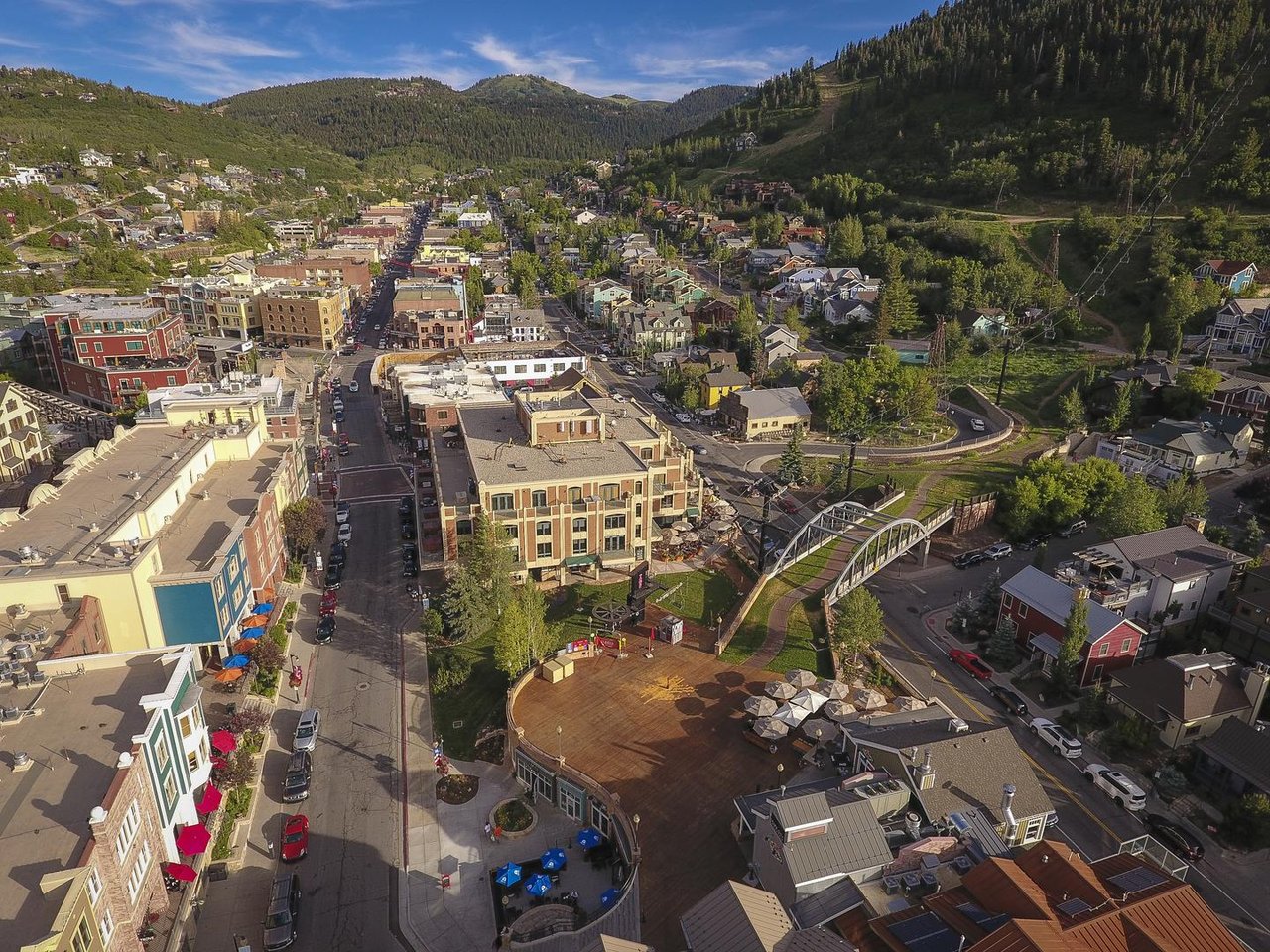 Aerial view capturing the charming mountain town setting, with treecovered hillsides and colorful local buildings surrounding the property area.