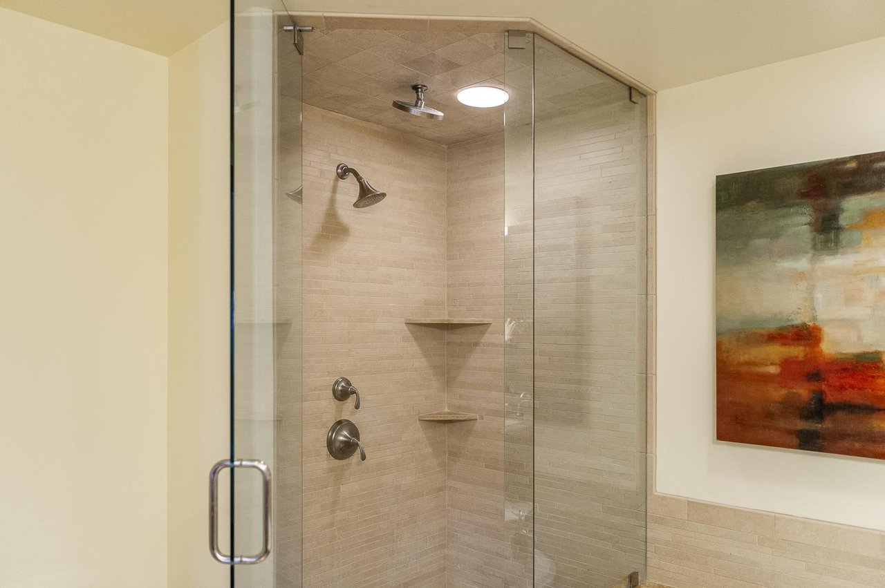 Main bathroom shower, sandstone tile walls and glass paneled door and wall