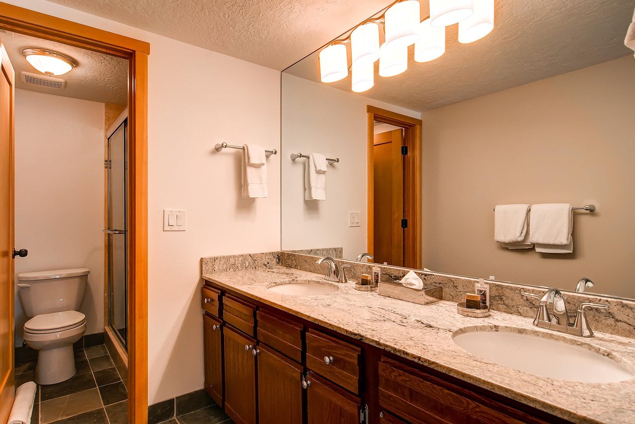The en suite bathroom has a two sink vanity and a separate water closet.