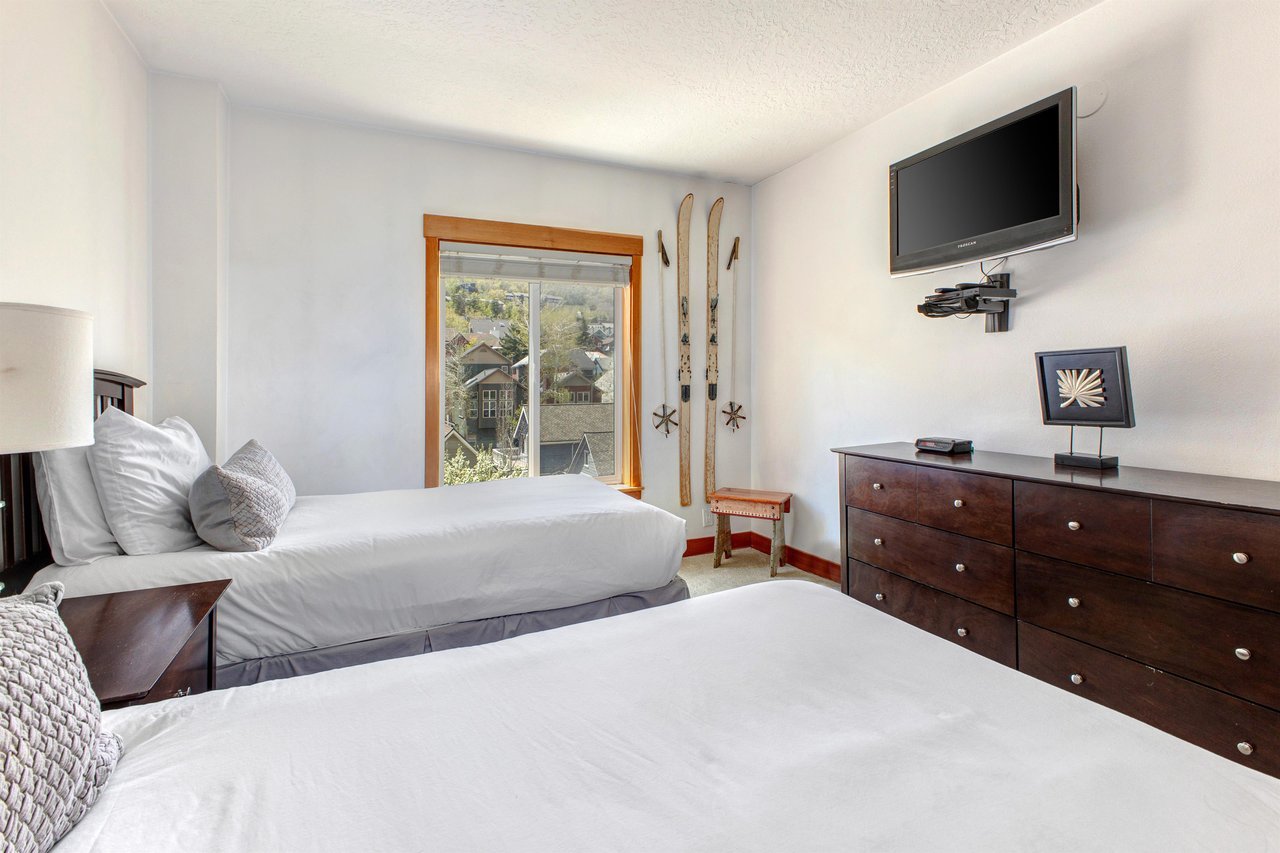 The second bedroom has two twin beds, wood dresser and flat screen TV.