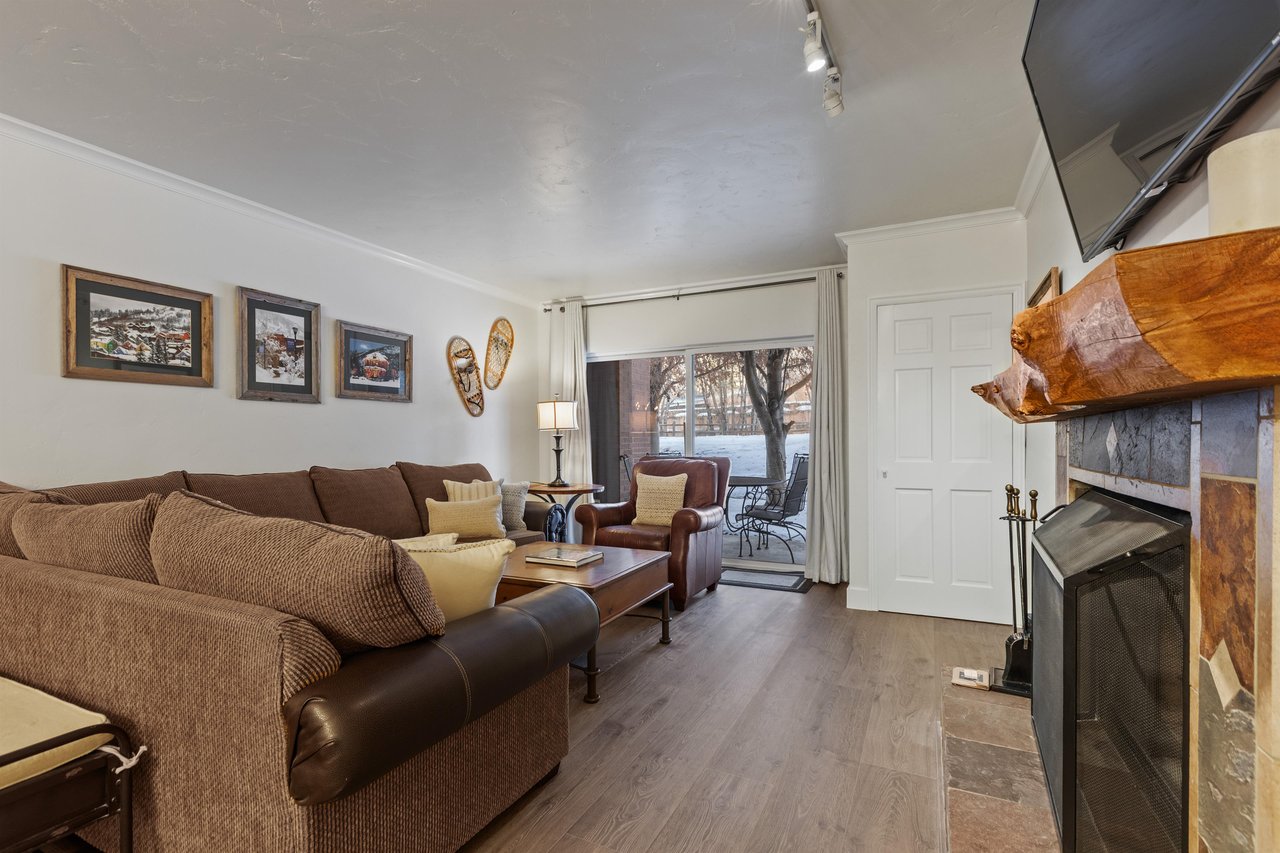 The living room has a large sectional sofa and sliding glass doors leading to a private patio.