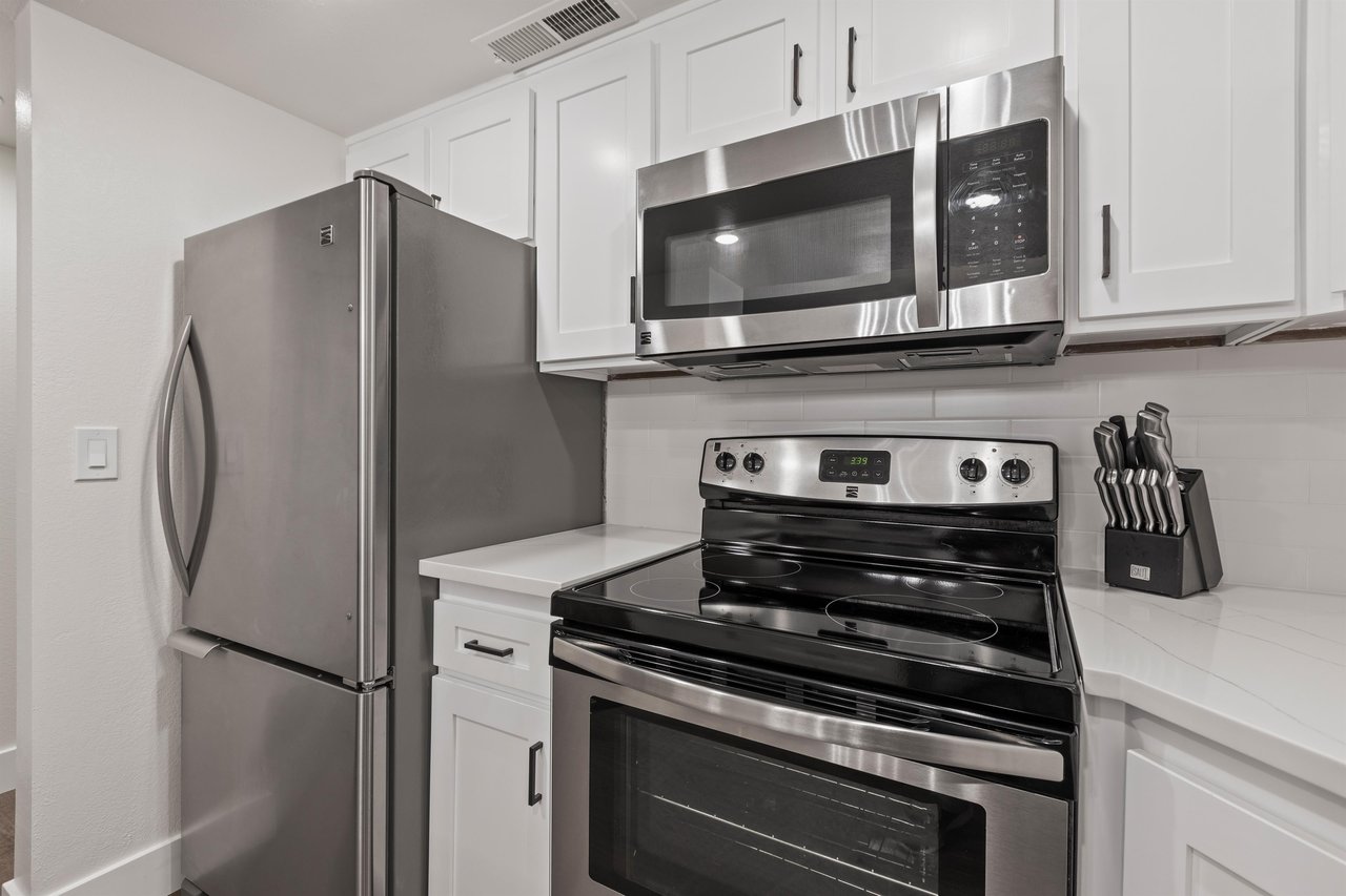 The kitchen has stainless steel appliances and white cabinets.