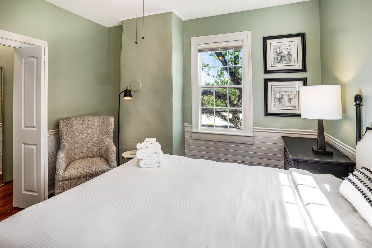 The main bedroom features a king size bed, comfortable arm chair, and walkin closet.