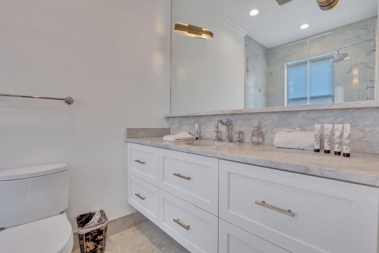 The luxurious ensuite bathroom features custom cut marble countertops, with a spacious vanity, equipped with an ample amount of storage.