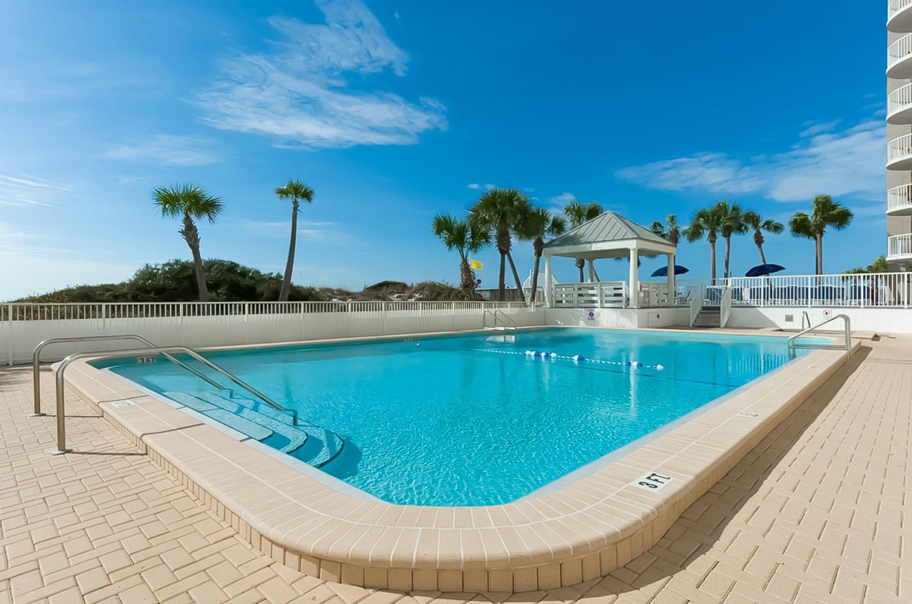 The complexs pool shimmers under sunny skies.