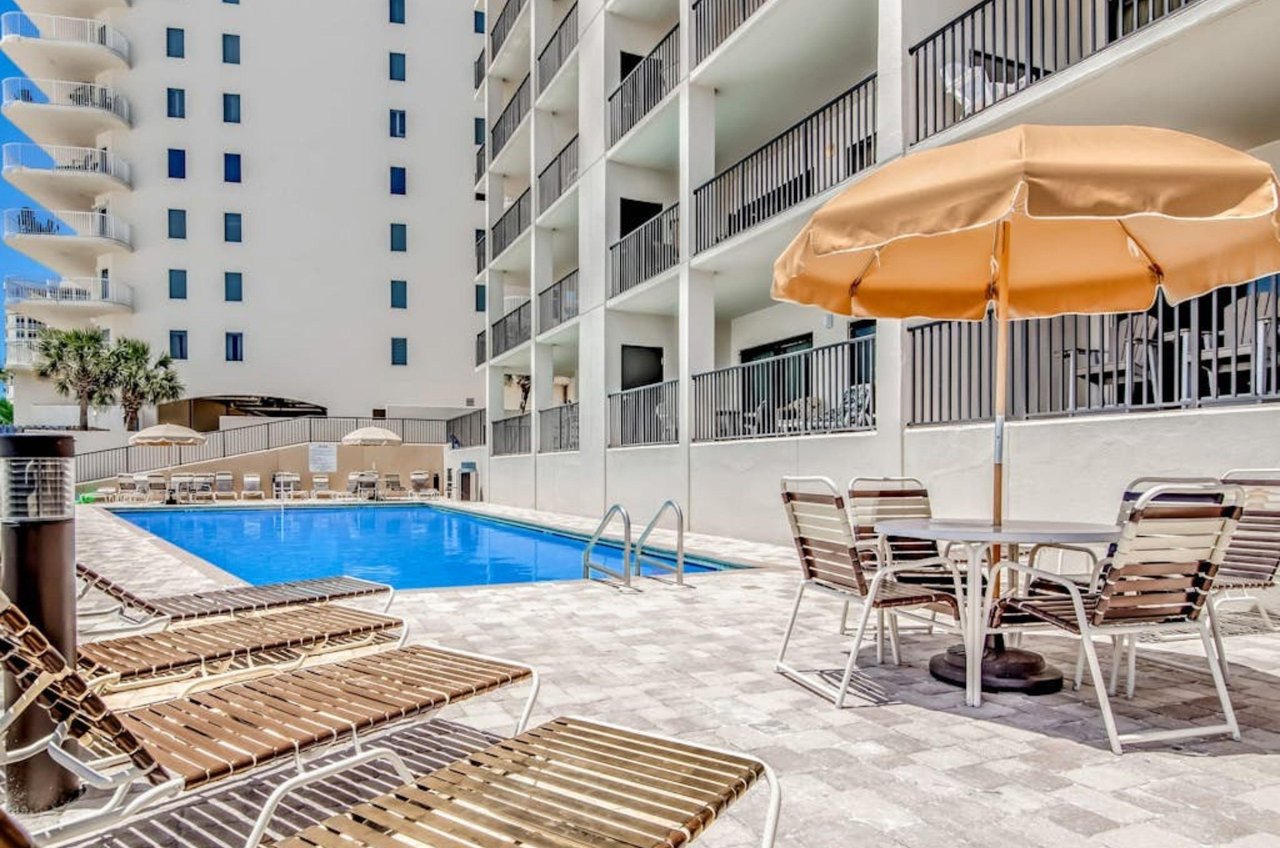 Lounge chairs and umbrellas next to the outdoor swimming pool at the Palms in Orange Beach Alabama