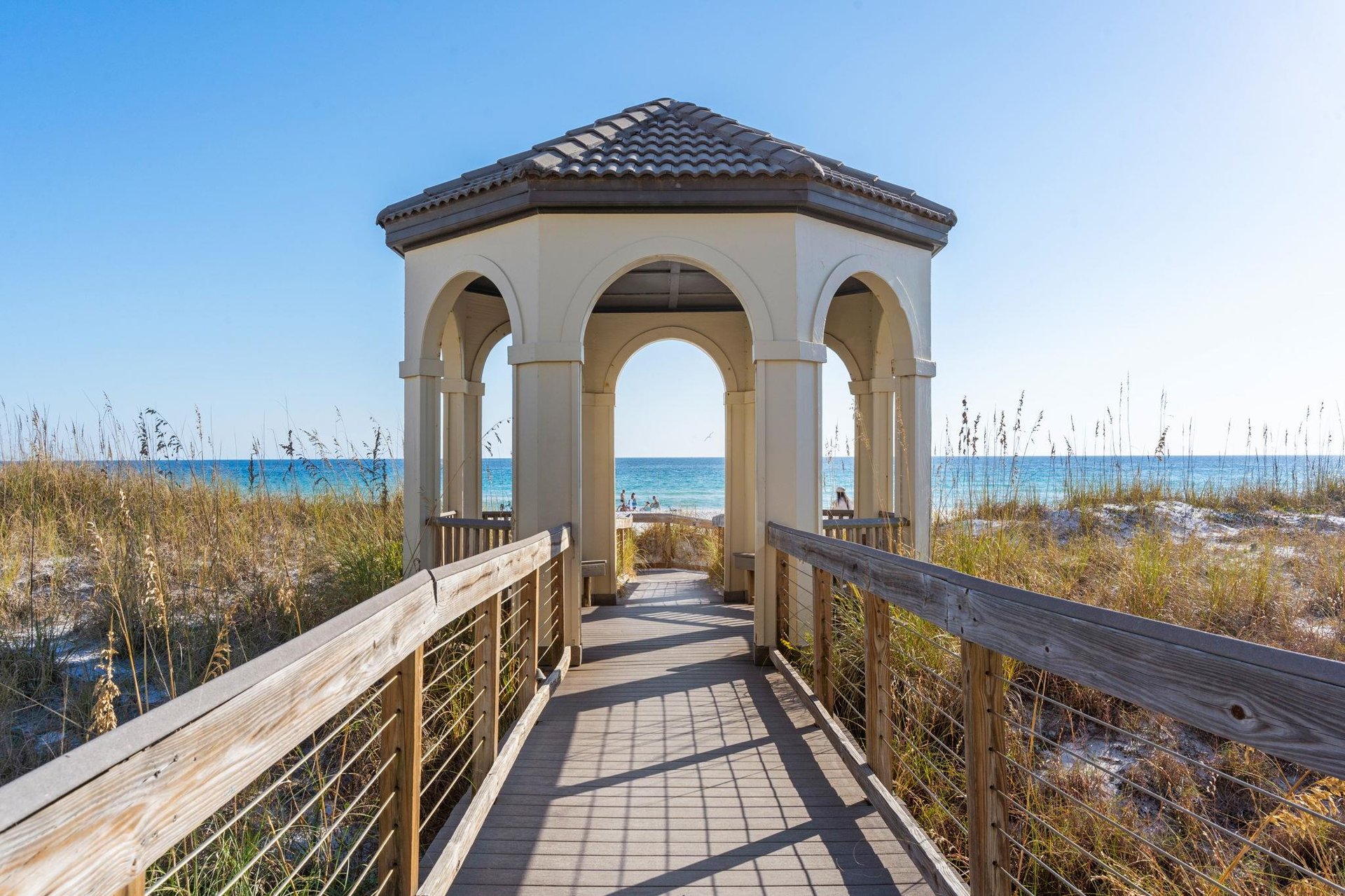 Elegant beachside pavilion with wooden boardwalk leads directly to pristine sandy shores and turquoise waters.