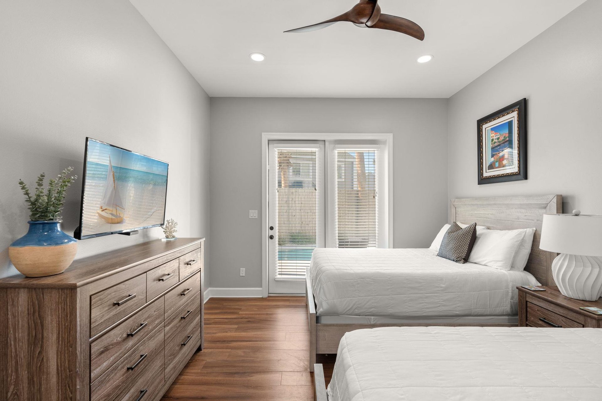 Relax in the serene bedroom with twin beds, warm wood floors, and French doors opening to your private pool area.