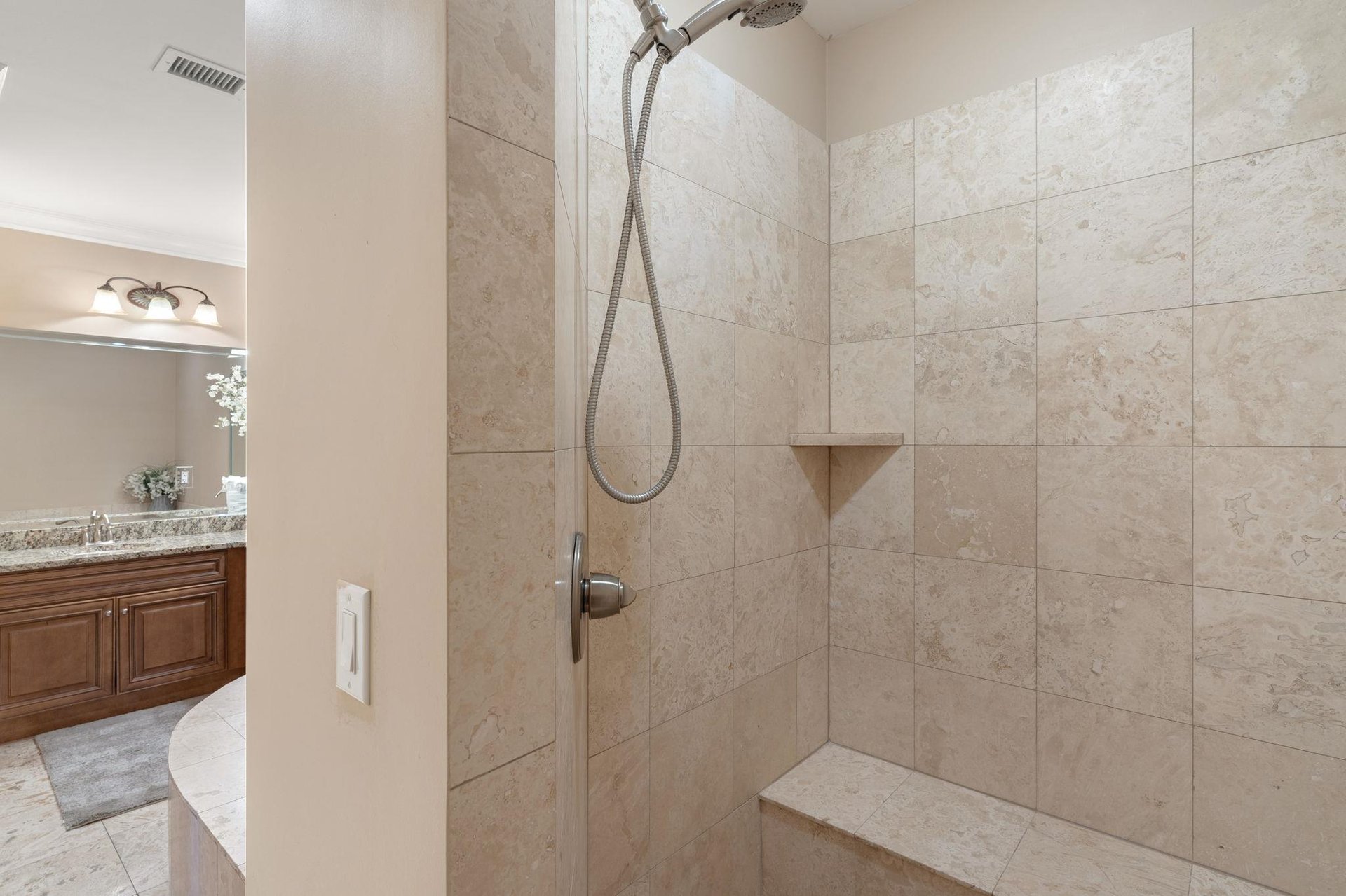 Step into your spacious walkin shower with elegant stone tiles and convenient corner shelf for your essentials.