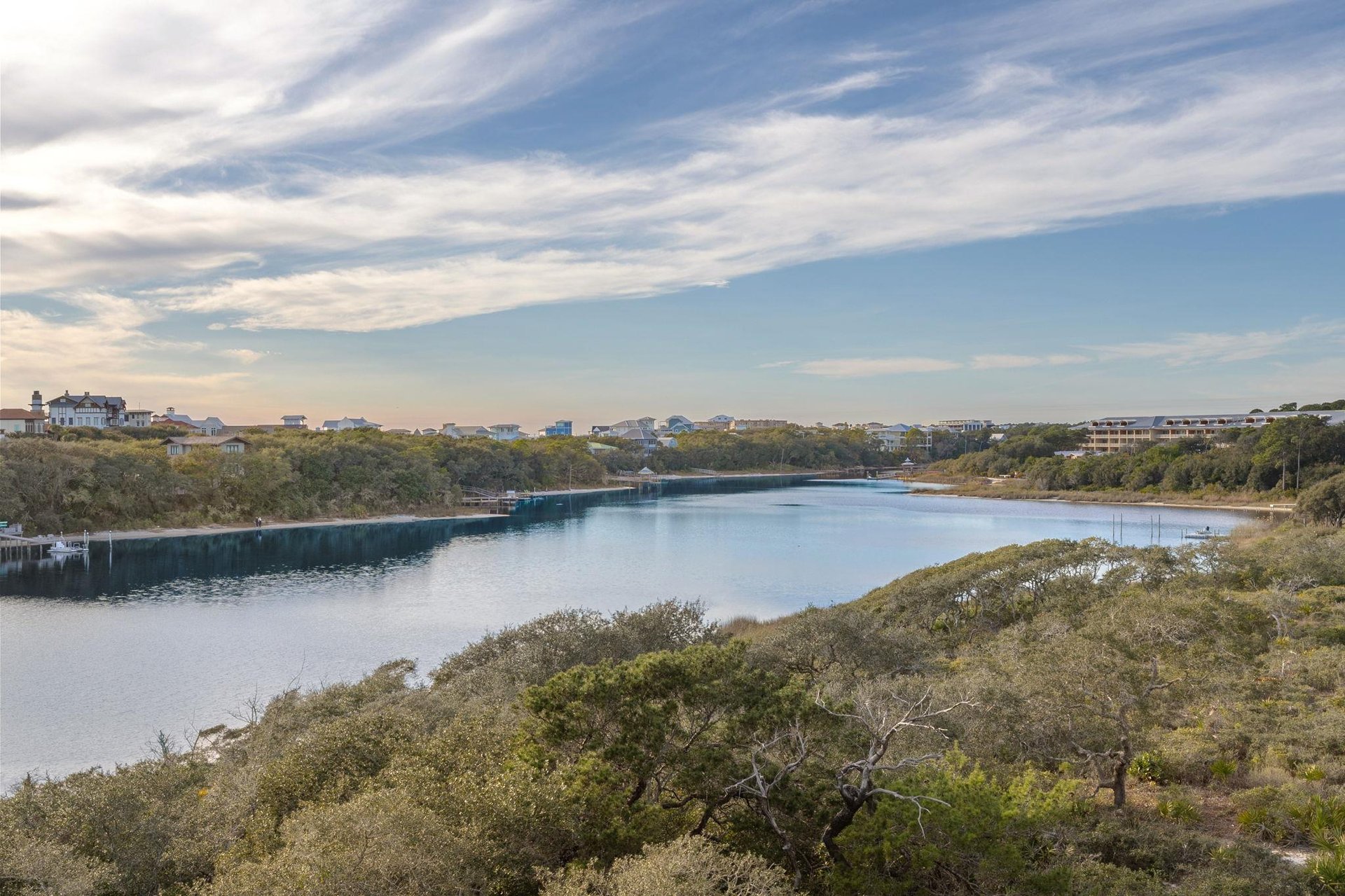 Scenic waterway winds through natural coastal landscape with charming vacation homes dotting the peaceful shoreline.