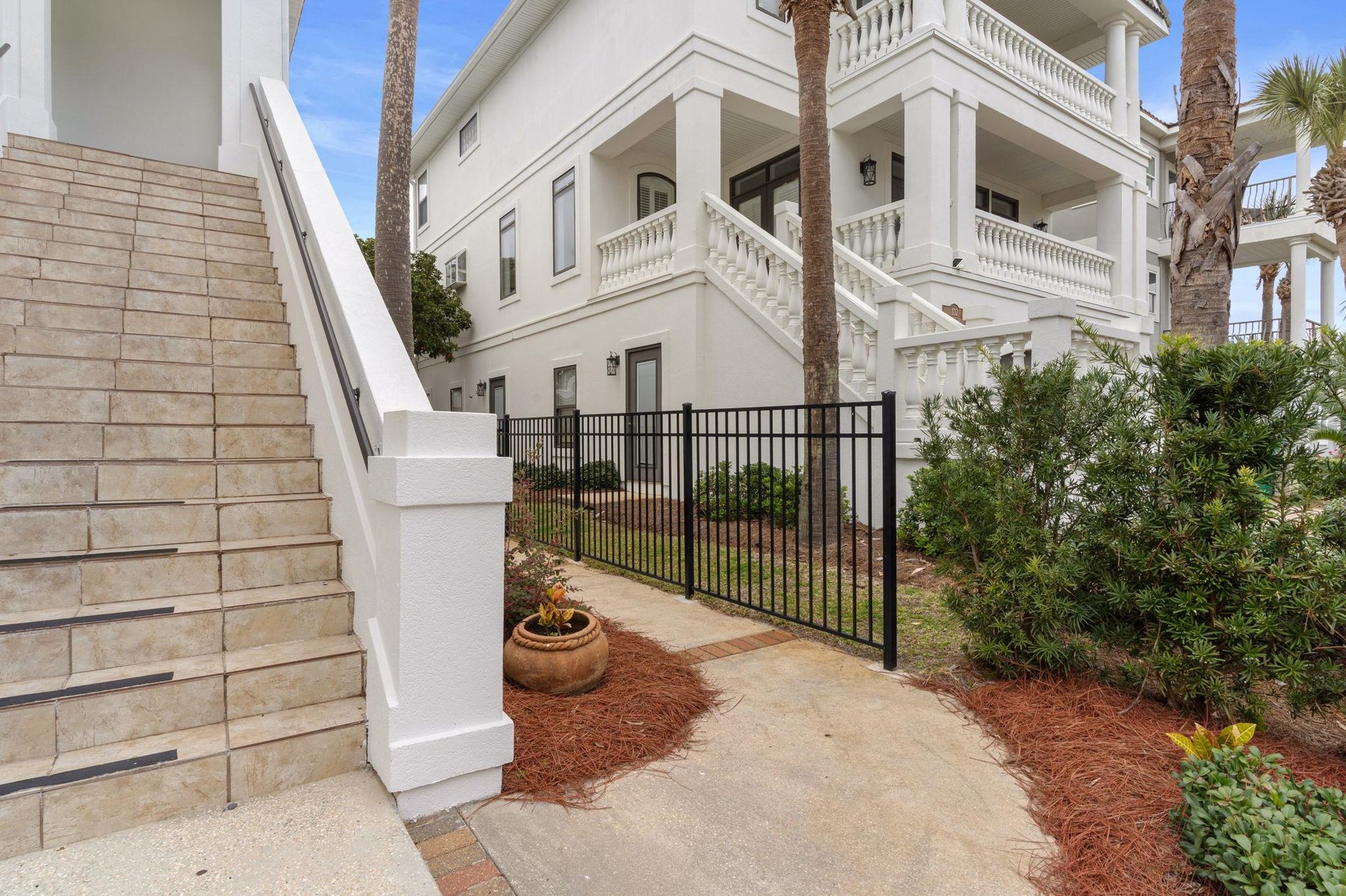 Elegant property entrance featuring classic white architecture with ornate balustrades and tropical landscaping.
