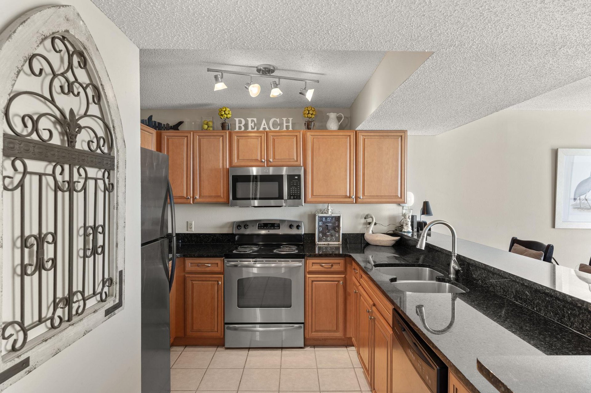 Fully equipped kitchen features granite counters, stainless appliances, and beachthemed charm for preparing memorable meals together.