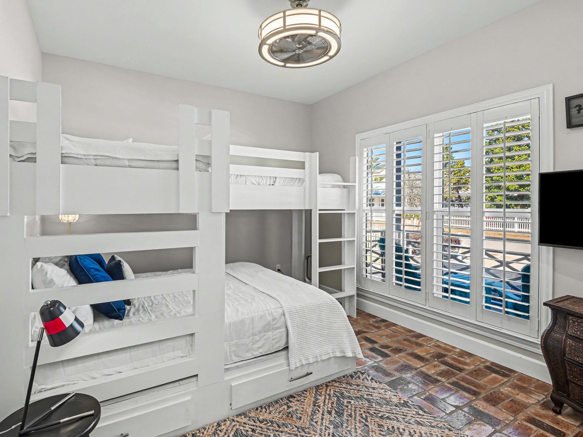 Sleep soundly in your bright bedroom featuring comfortable bunk beds and poolside views through elegant shutters.