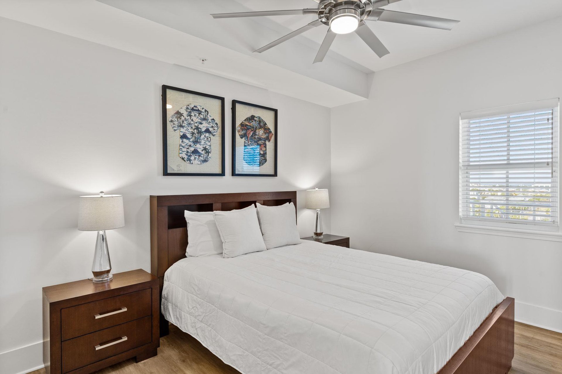 This serene queen bedroom features plush bedding and a gentle ceiling fan.,