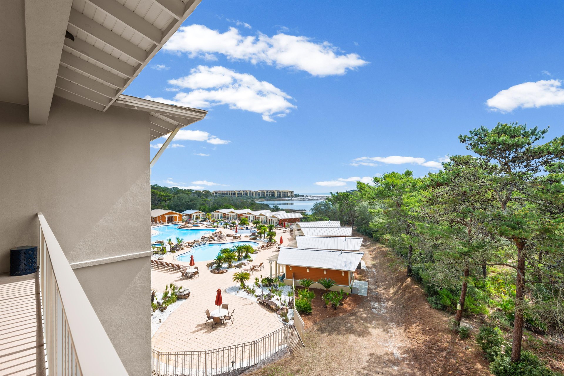 Resort complex featuring four outdoor pools surrounded by lush green trees under brilliant blue skies.