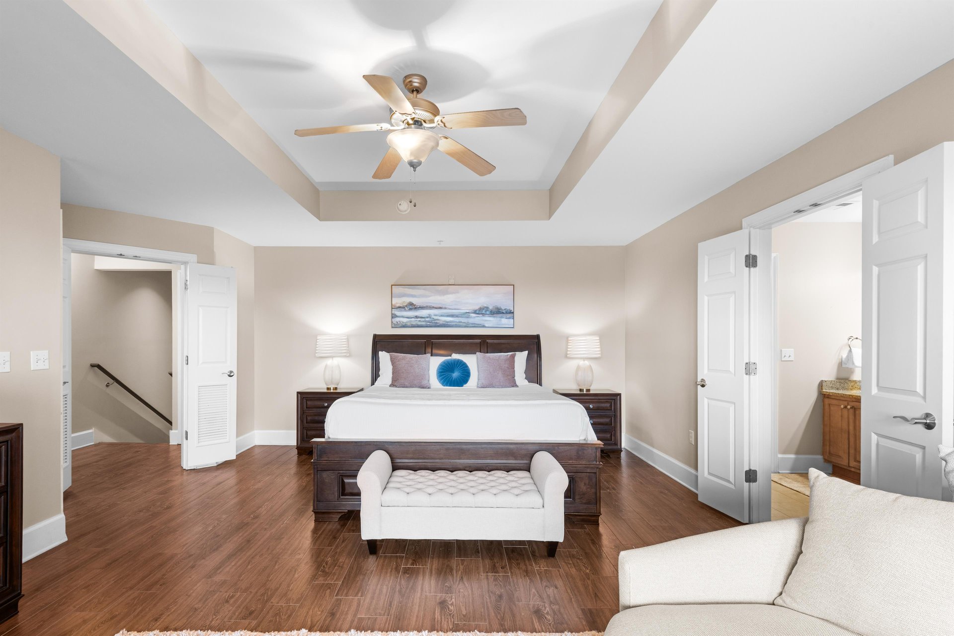 Relax in this spacious king master suite with coffered ceilings, rich hardwood floors, and elegant furnishings creating the perfect sanctuary.