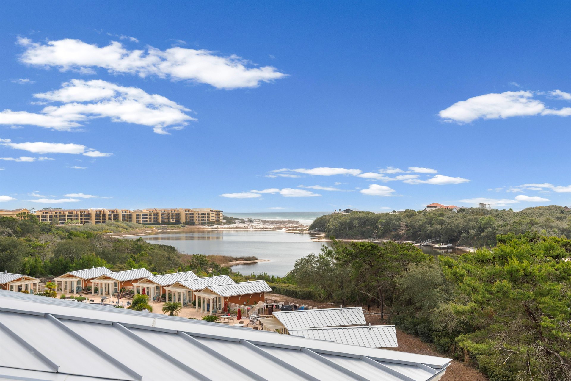 Elevated coastal view showcasing the serene waterway, lush vegetation, and nearby resort accommodations under expansive blue skies.