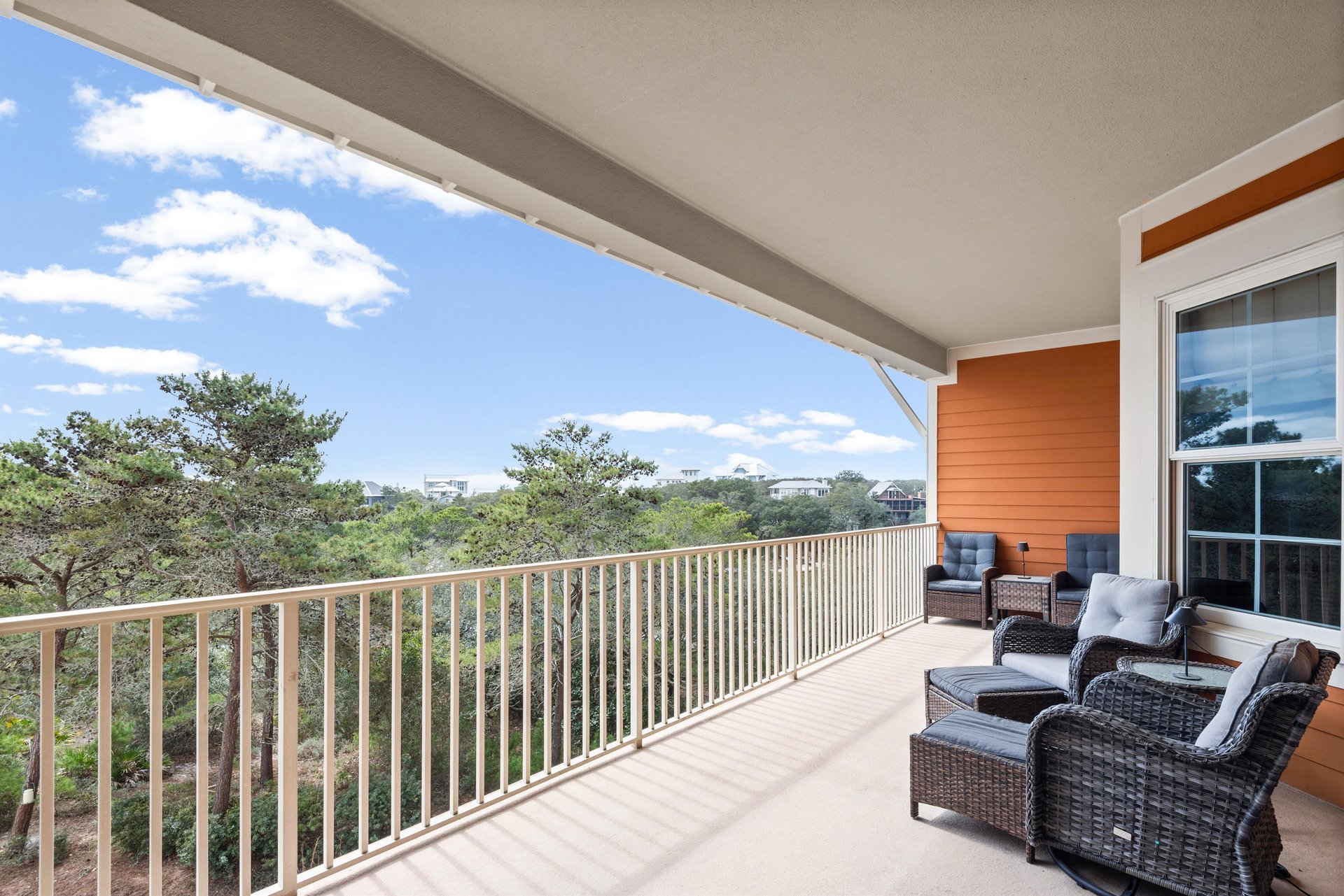 Relax in your private balcony sanctuary with cushioned wicker seating while taking in sweeping coastal views and blue skies.