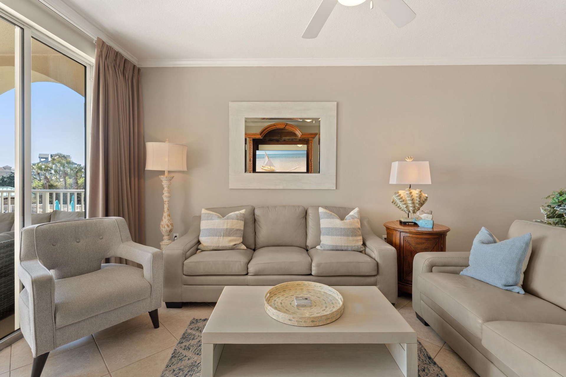 Unwind in your serene living room with plush seating, coastal decor, and natural light streaming through expansive windows.