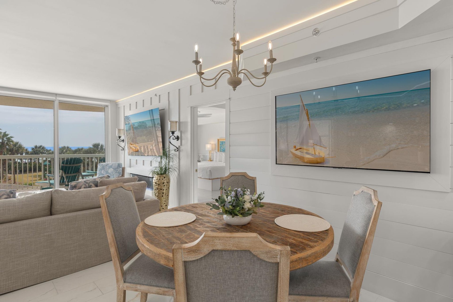 Dine beneath elegant chandelier light while oceaninspired artwork sets the mood.