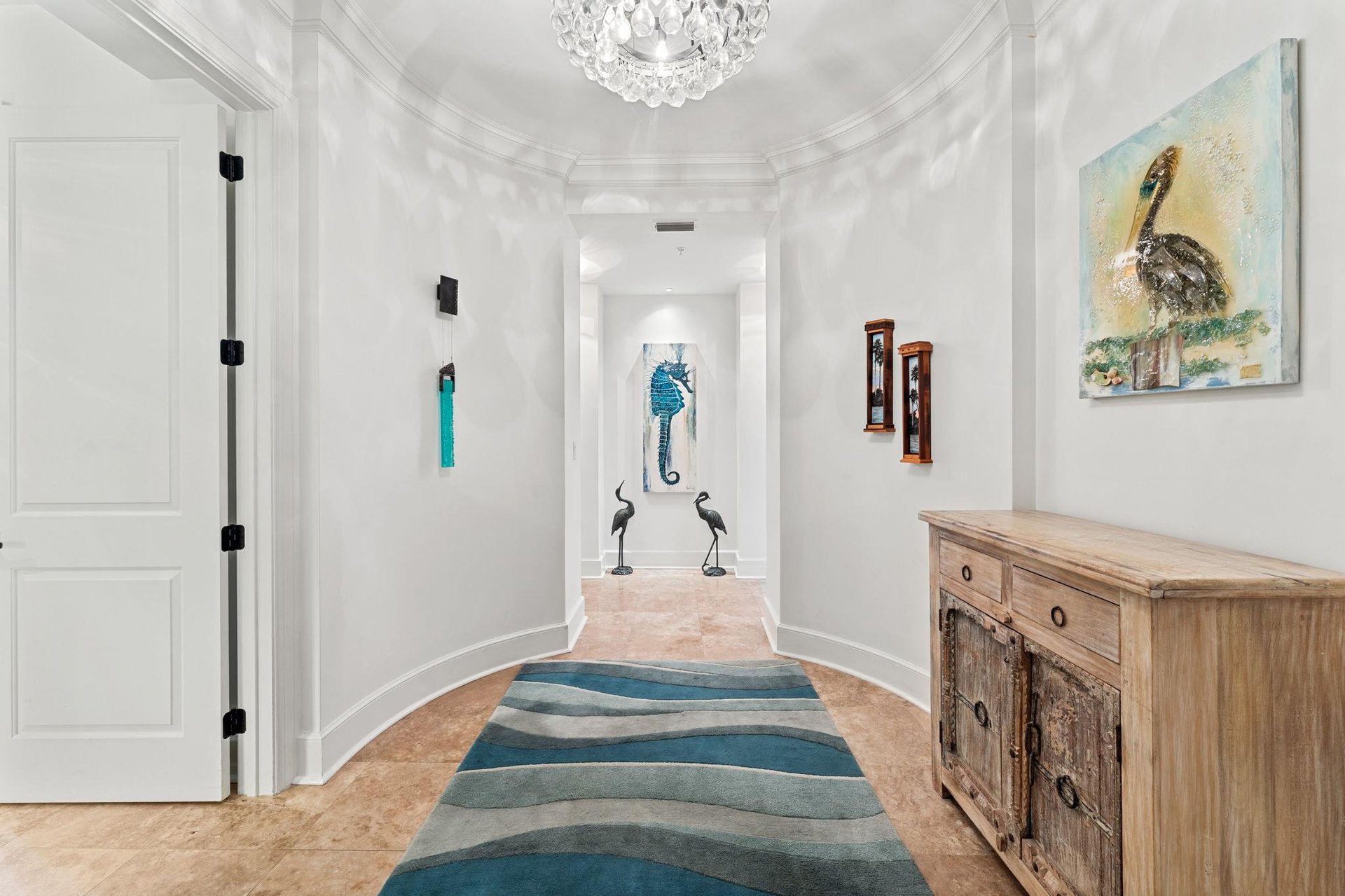 Step into 2110s elegant entryway where coastal charm meets sophisticated design, complete with sparkling chandelier and curated artwork welcoming you
