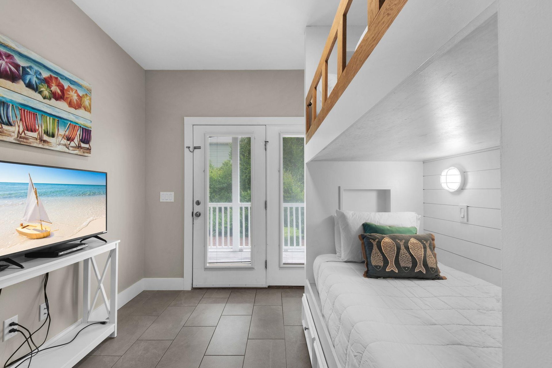 Unwind in the bunk room with cheerful beach decor, a comfortable daybed, and direct balcony access. Perfect for cozy evenings or quiet moments.