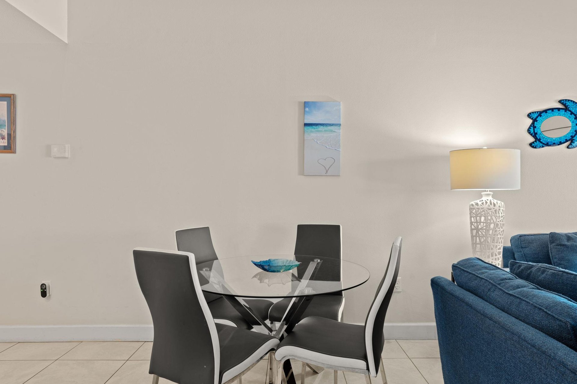 Gather around this sleek glass dining table, where modern style meets coastal charm. The soft lighting and oceaninspired décor create a welcoming atmosphere for your meals together.