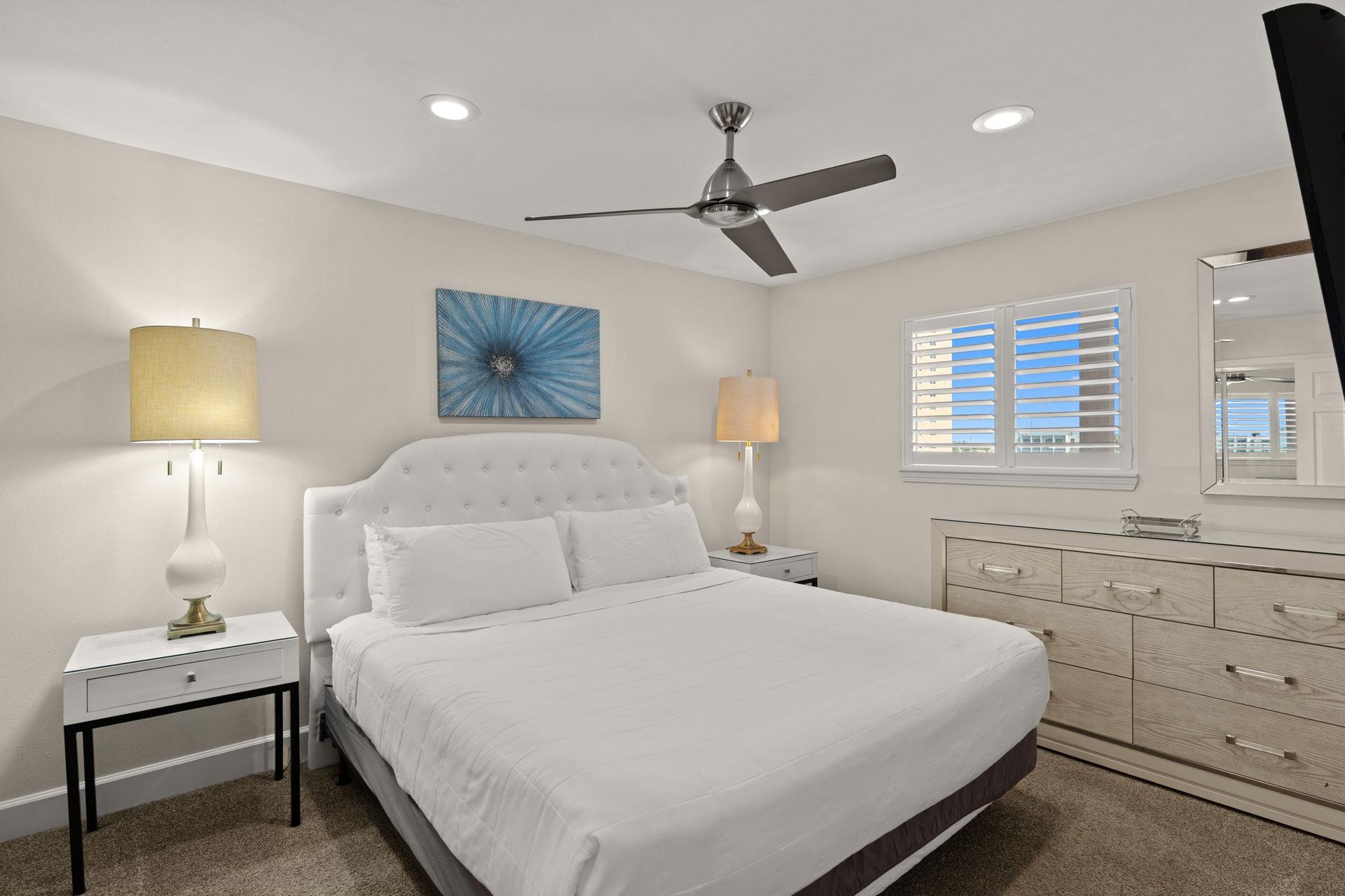 1st Floor Bedroom 1  Drift off in plush comfort beneath soft linens. Natural light filters through plantation shutters, while the ceiling fan keeps you cool. This serene retreat invites your most res