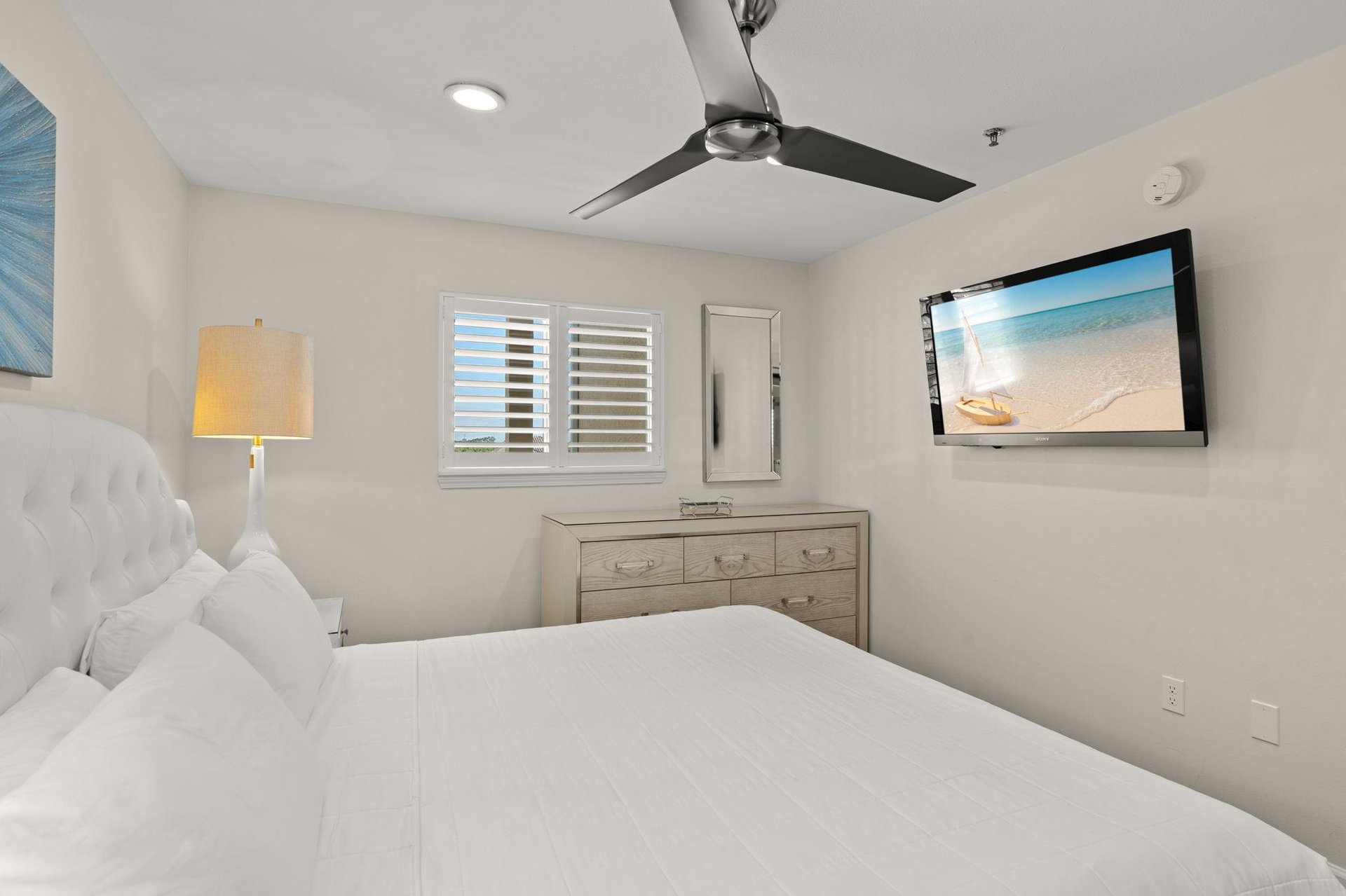 Sink into crisp white linens under a gentle ceiling fan, and wallmounted TV setting the tone for your peaceful beachside retreat.