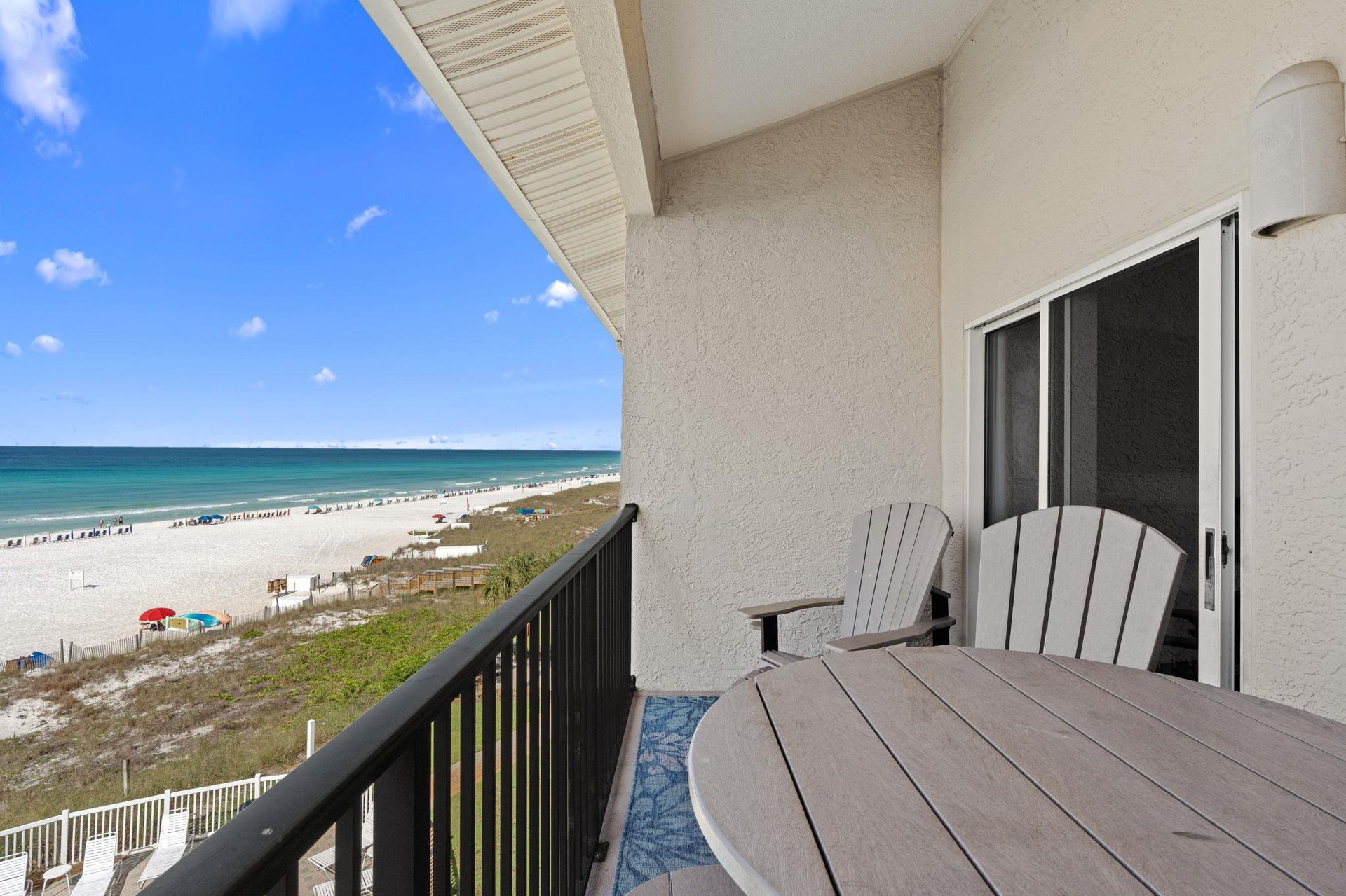 The balcony offers unobstructed beachfront views with comfortable seating overlooking white sand, turquoise waters, and sunbathers below—perfect for morning coffee or sunset cocktails.