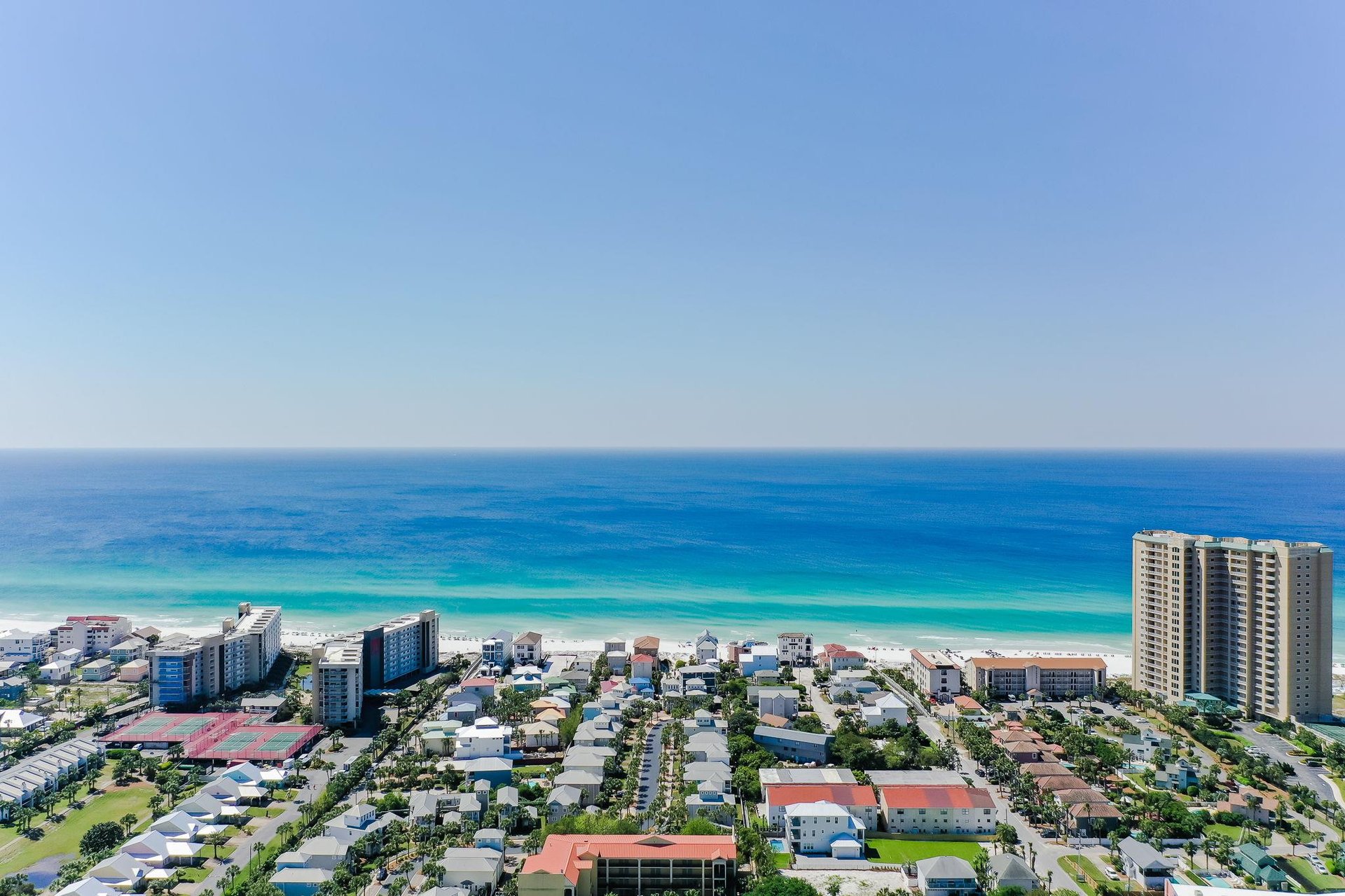 A stunning coastal community meets pristine turquoise waters along this beautiful shoreline, showcasing the vibrant beachfront neighborhood and surrounding area.