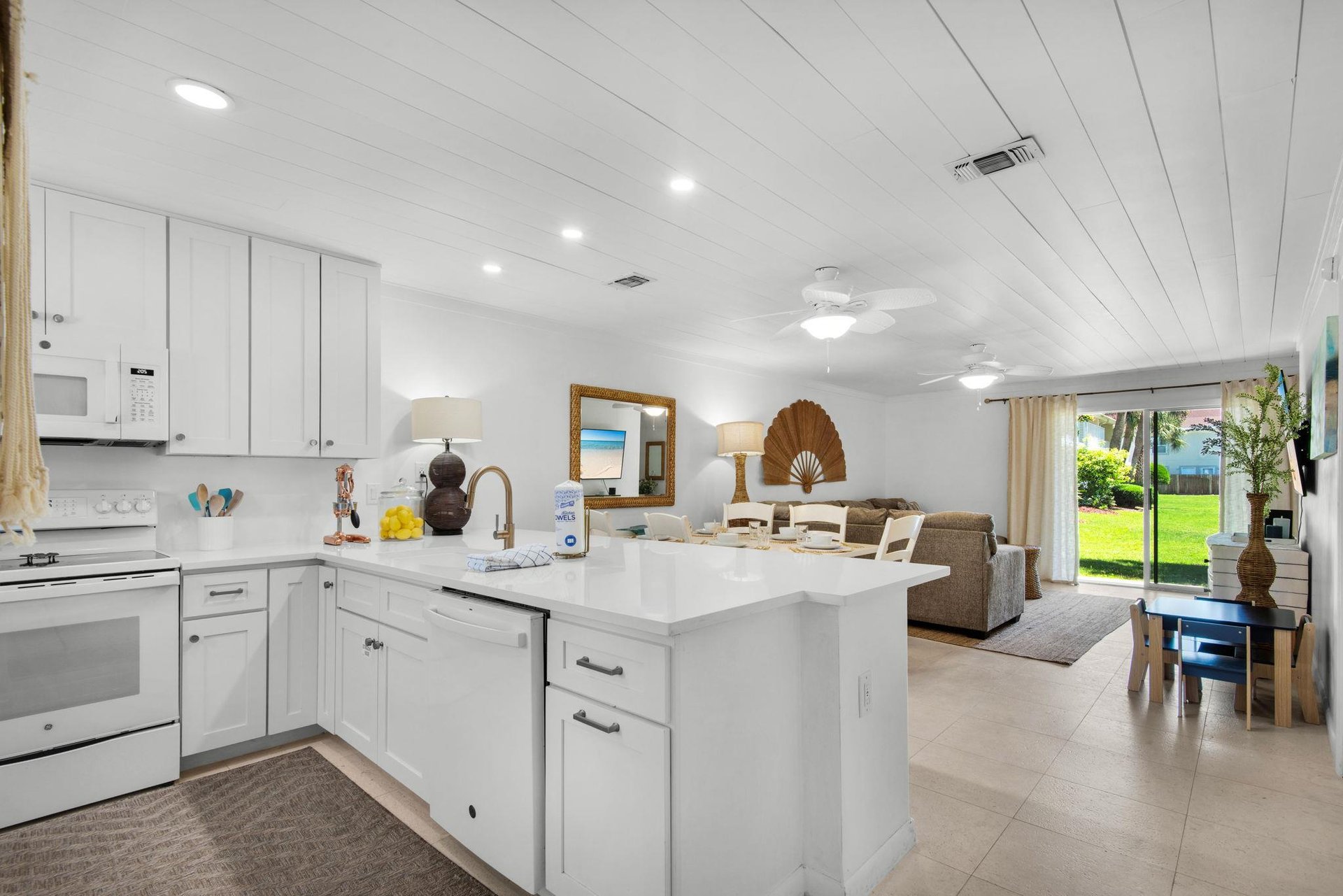 Your openconcept retreat features a bright coastal kitchen flowing into a relaxed living space, with views of lush greenery just outside your door.
