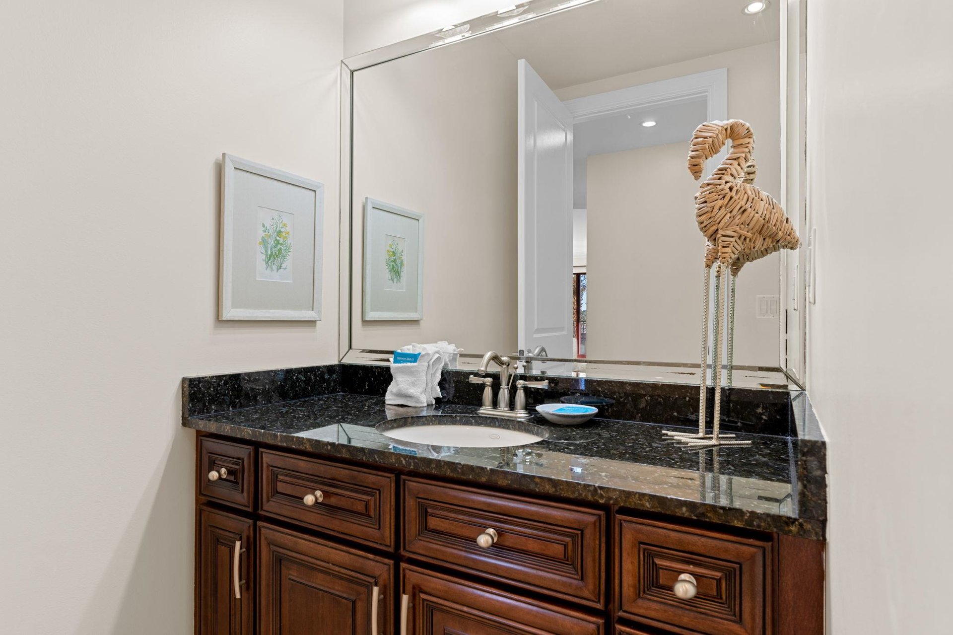 Half bathroom located just off the kitchen area, with granite countertops and warm wood cabinetry.