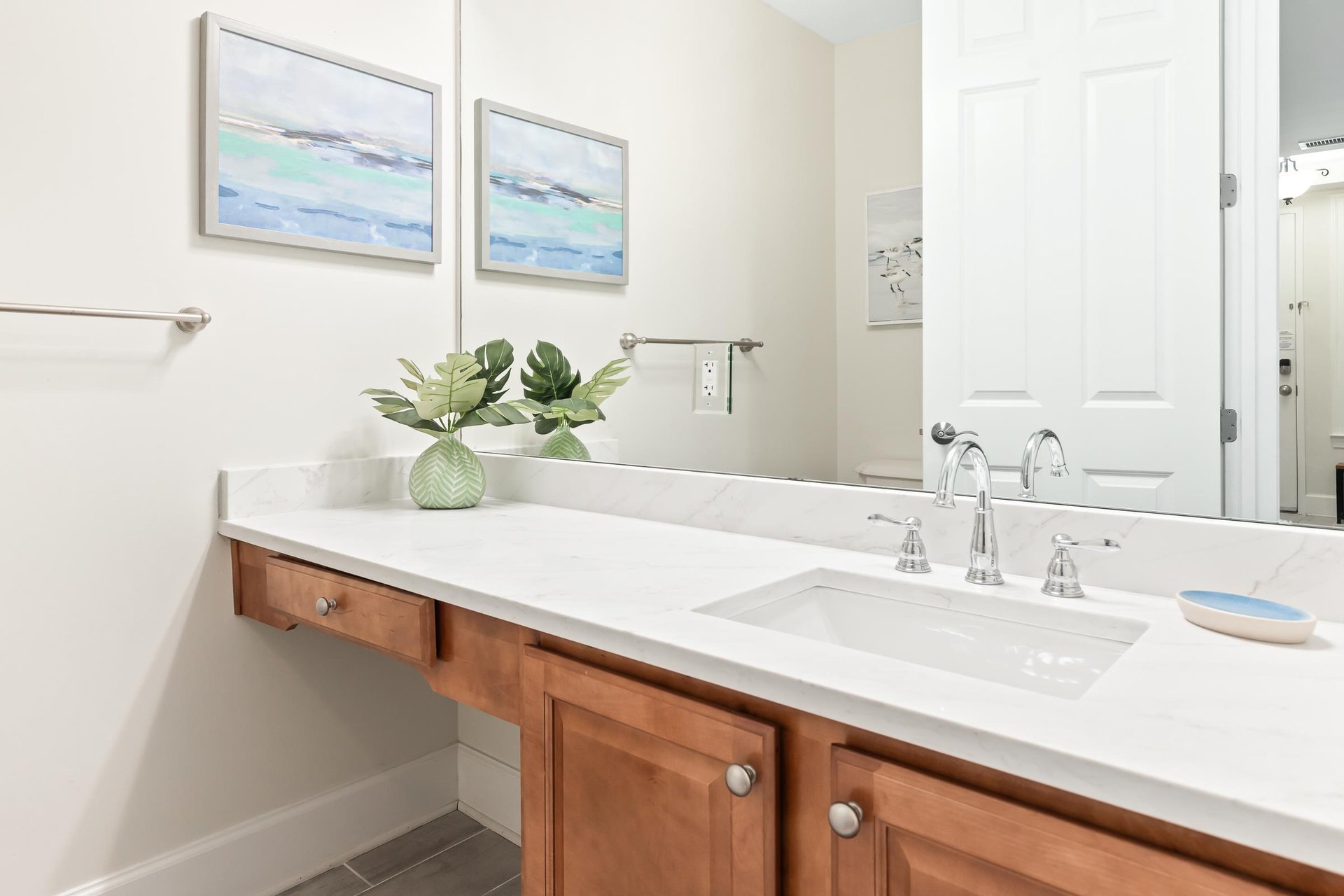Refresh in your bright, stylish bathroom with coastalinspired art, warm wood accents, and a pristine vanity designed for your comfort.