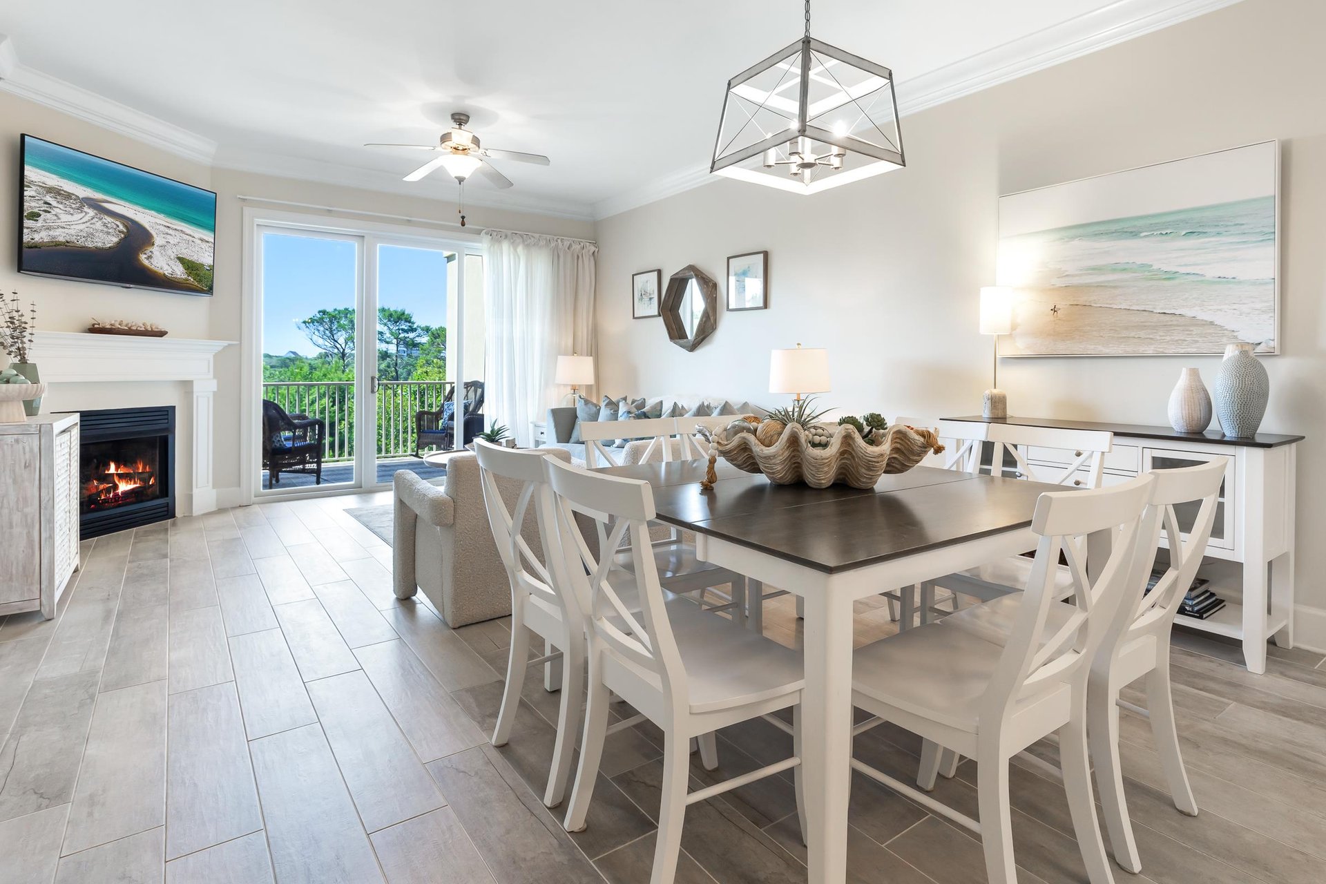 Your openconcept living and dining area features coastal elegance with a cozy fireplace, oceanview balcony access, and seating for eight beneath soft lighting, perfect for relaxed evenings together.