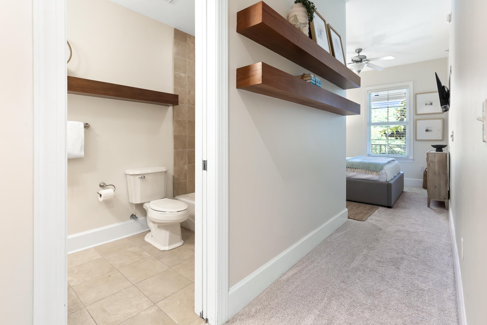 Your private retreat features open floating shelves, a cozy seating nook, and an ensuite bathroom with a walkin shower, all bathed in soft natural light.