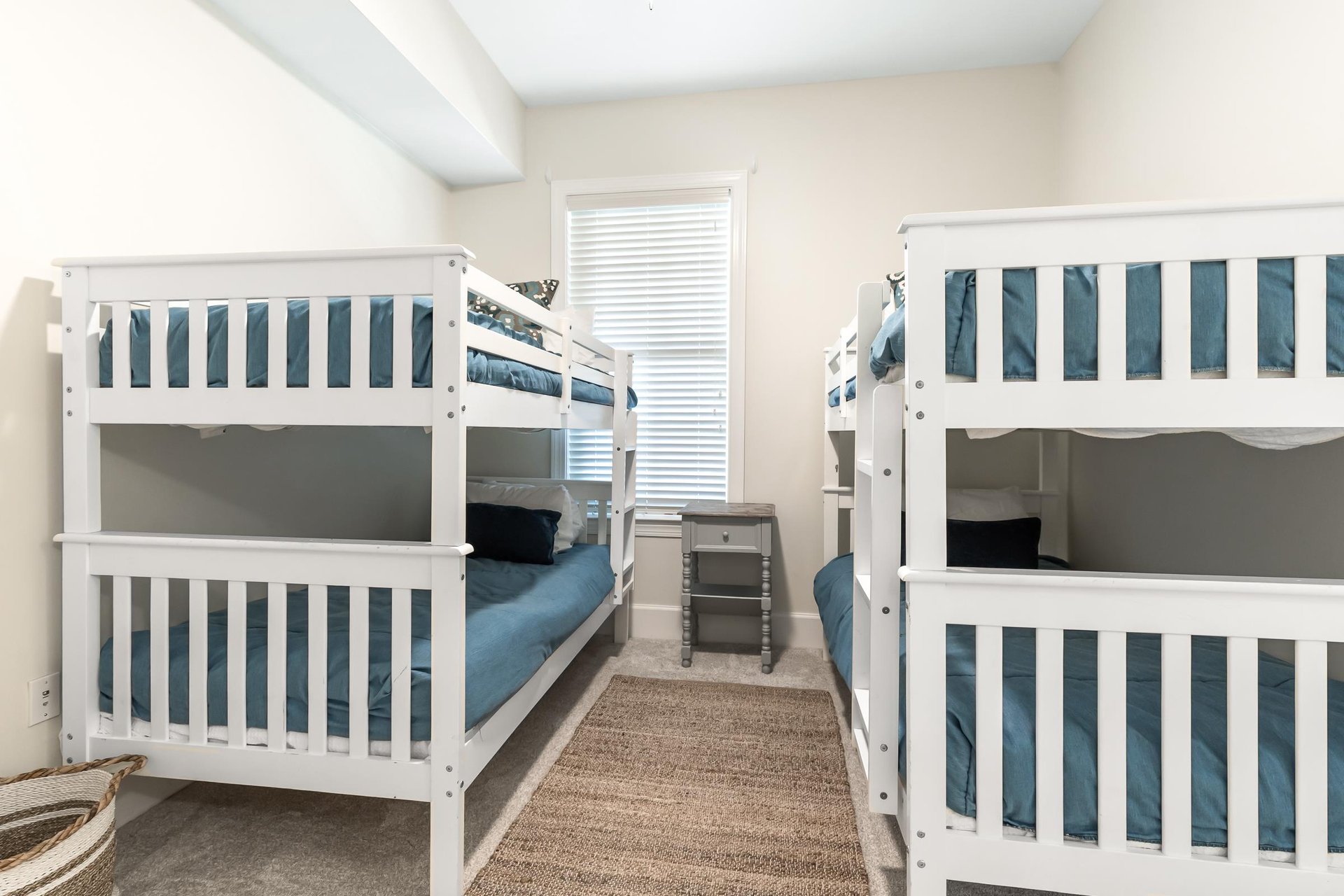 Perfect for families or groups, this bright room features two white bunk beds with deep teal linens, offering cozy sleeping space for kids or friends traveling together.
