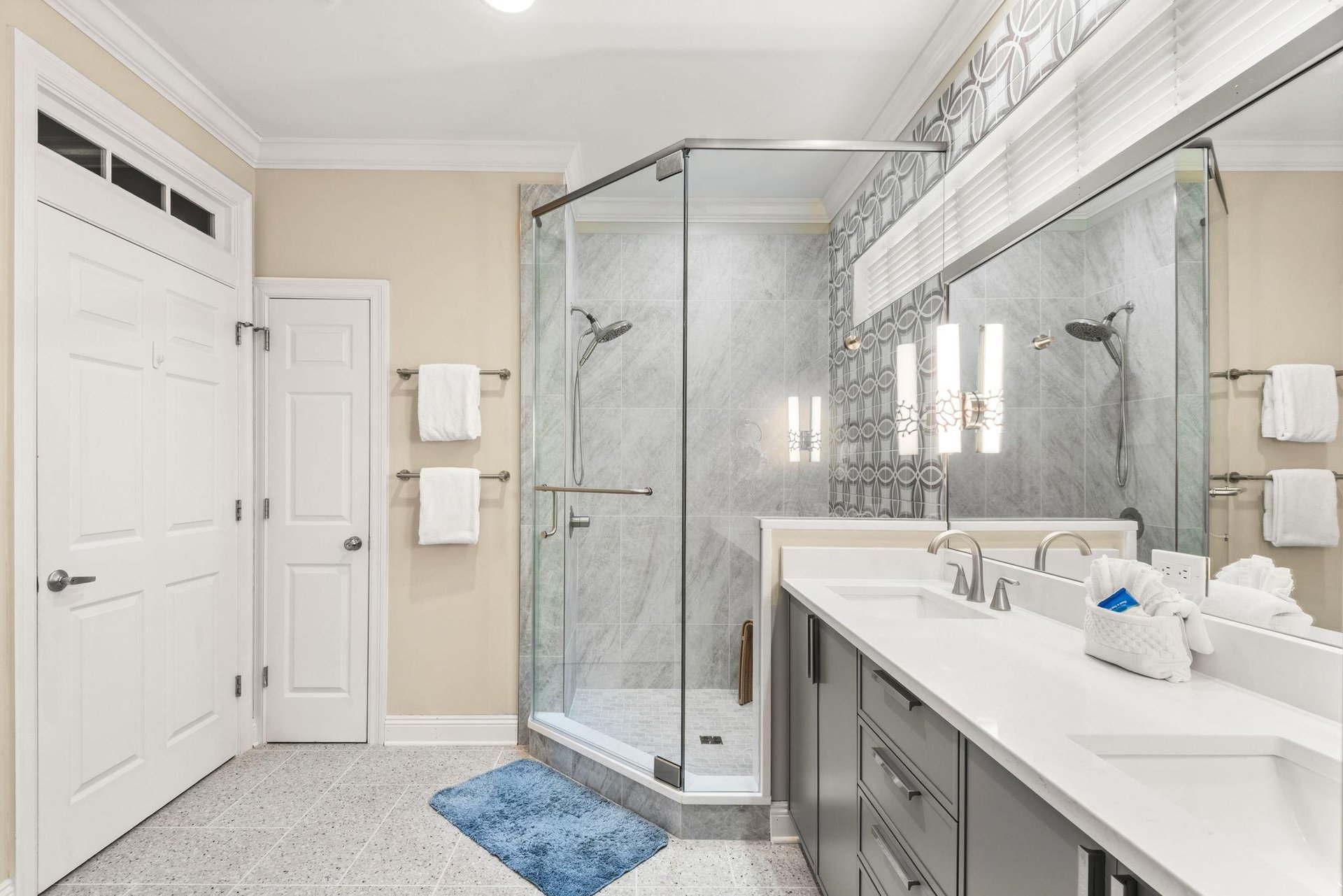 The elegant primary bathroom features a spacious walkin shower with marble tile, dual vanity sinks, and designer fixtures that blend style with comfort.